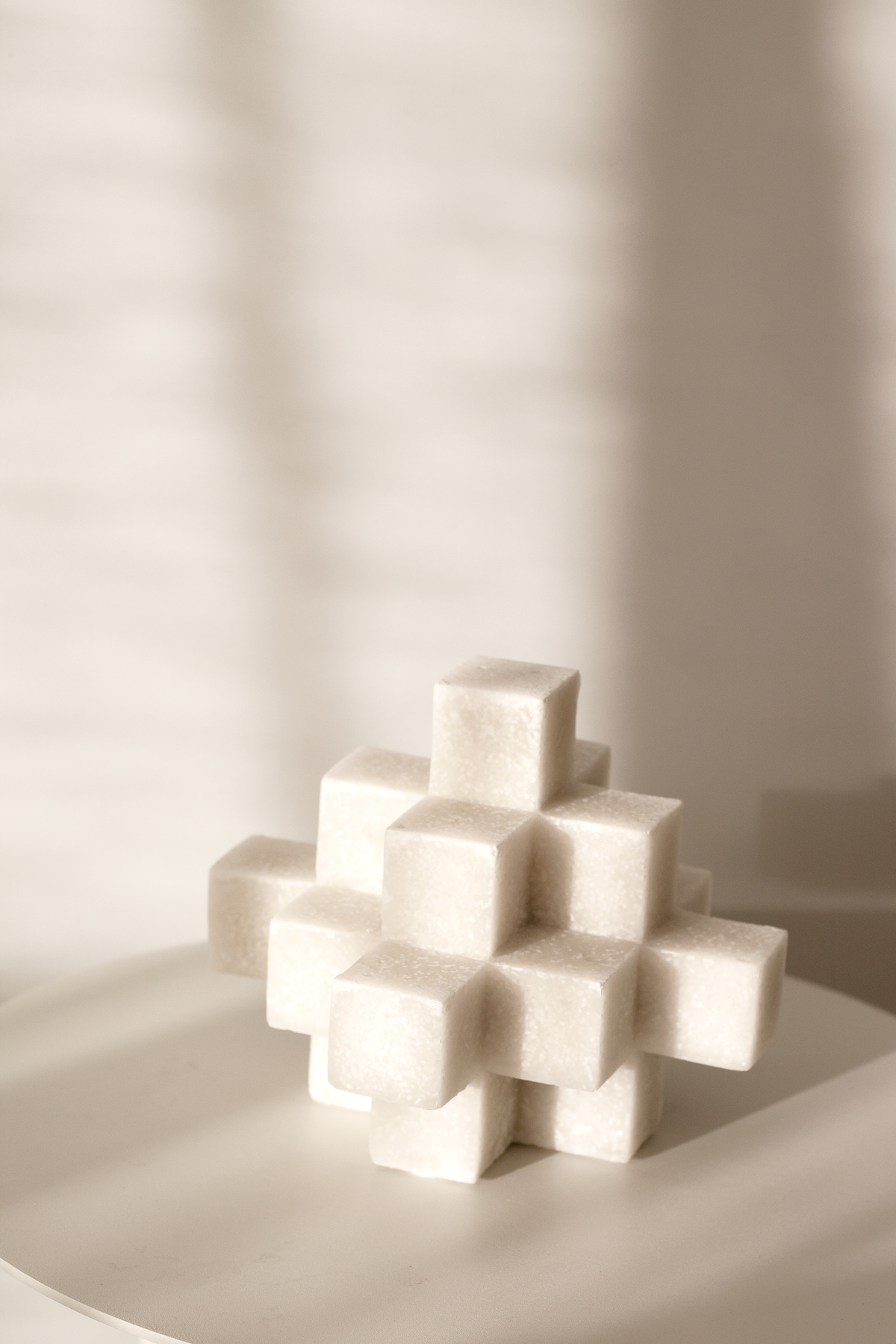 White Cubism sculpture in low sunlight on a pale surface