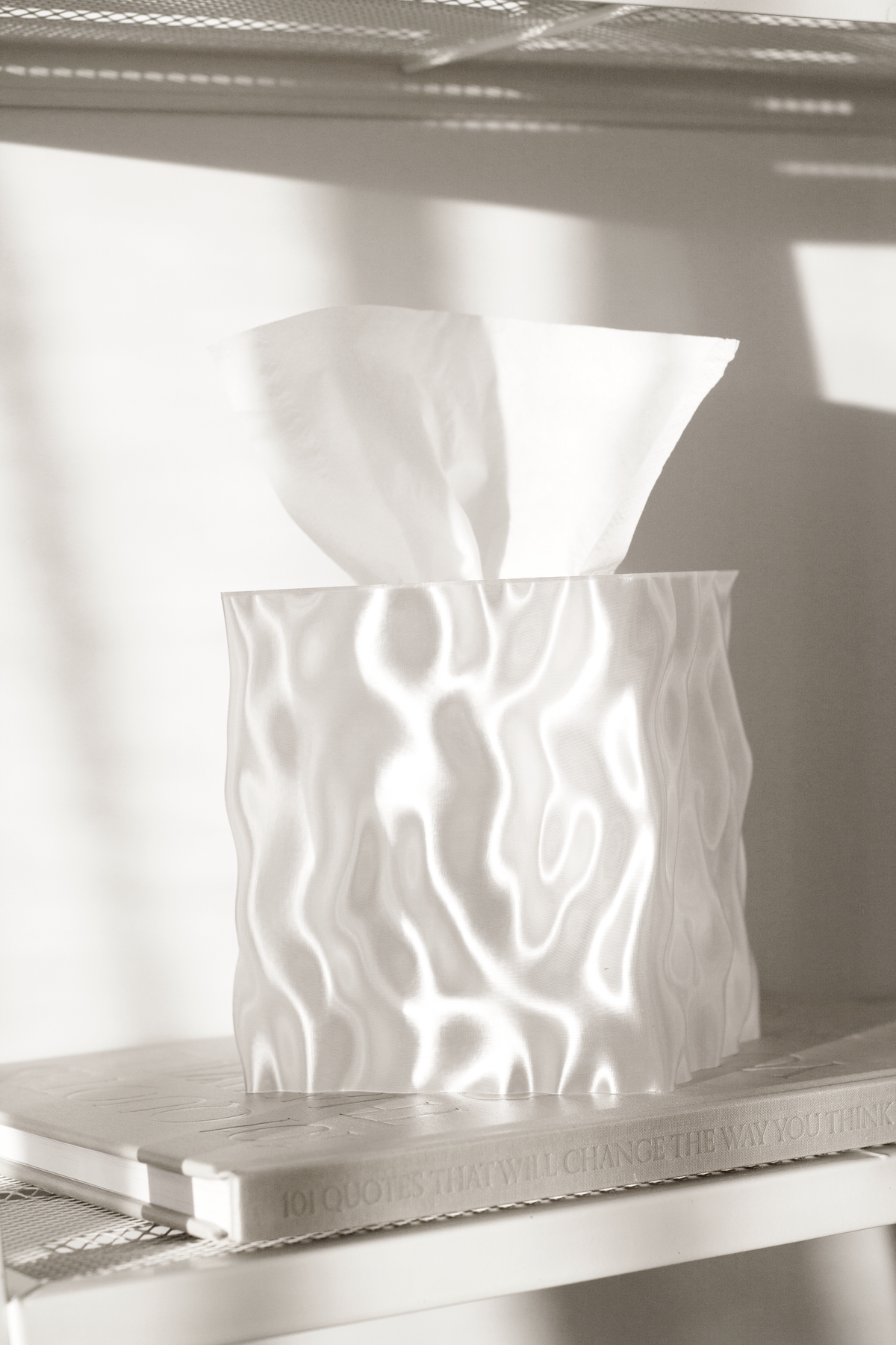 Clear Flow tissue box cover lit from within on a glass shelf