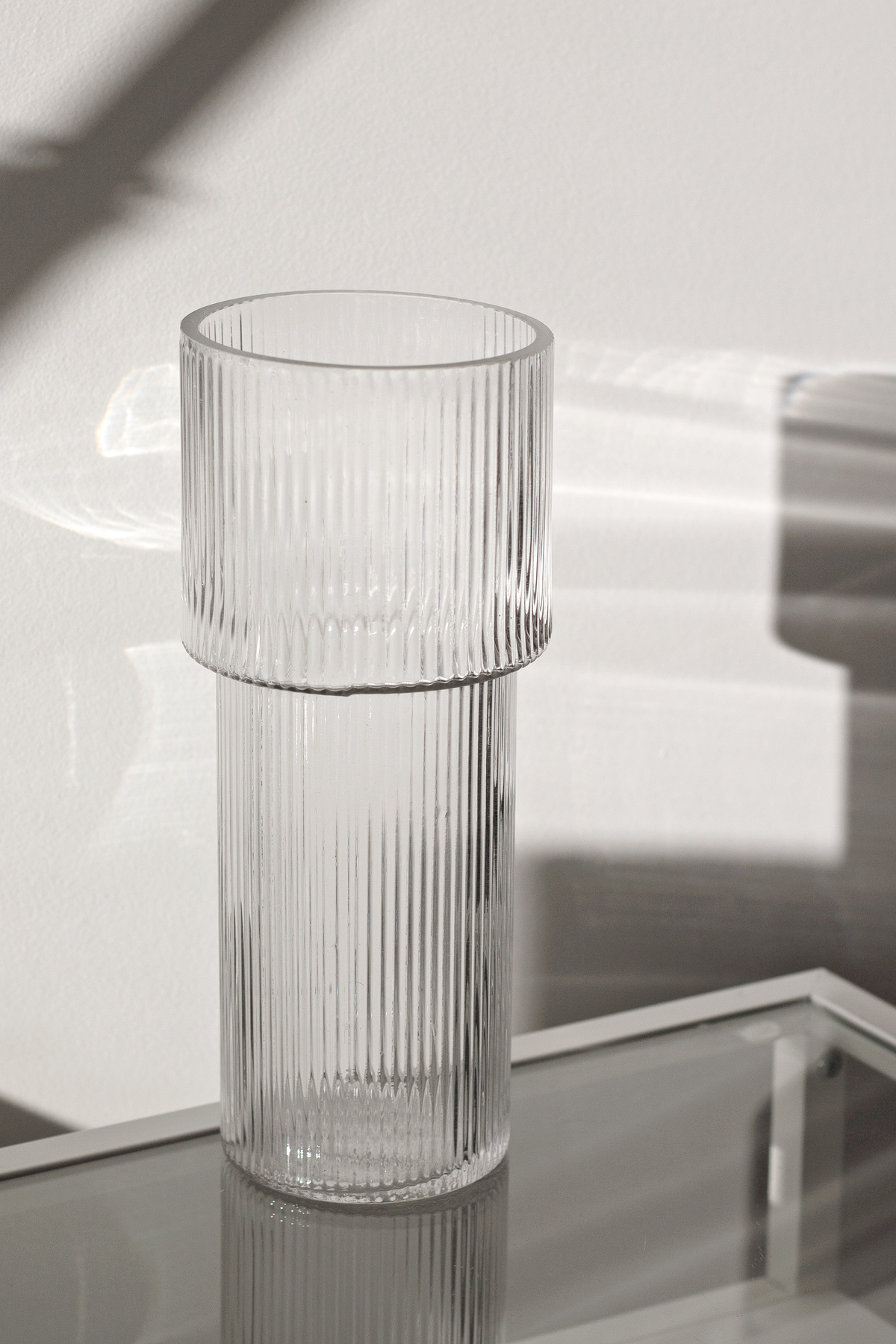 Ribbed glass vase on a mirrored surface, showing the stepped join