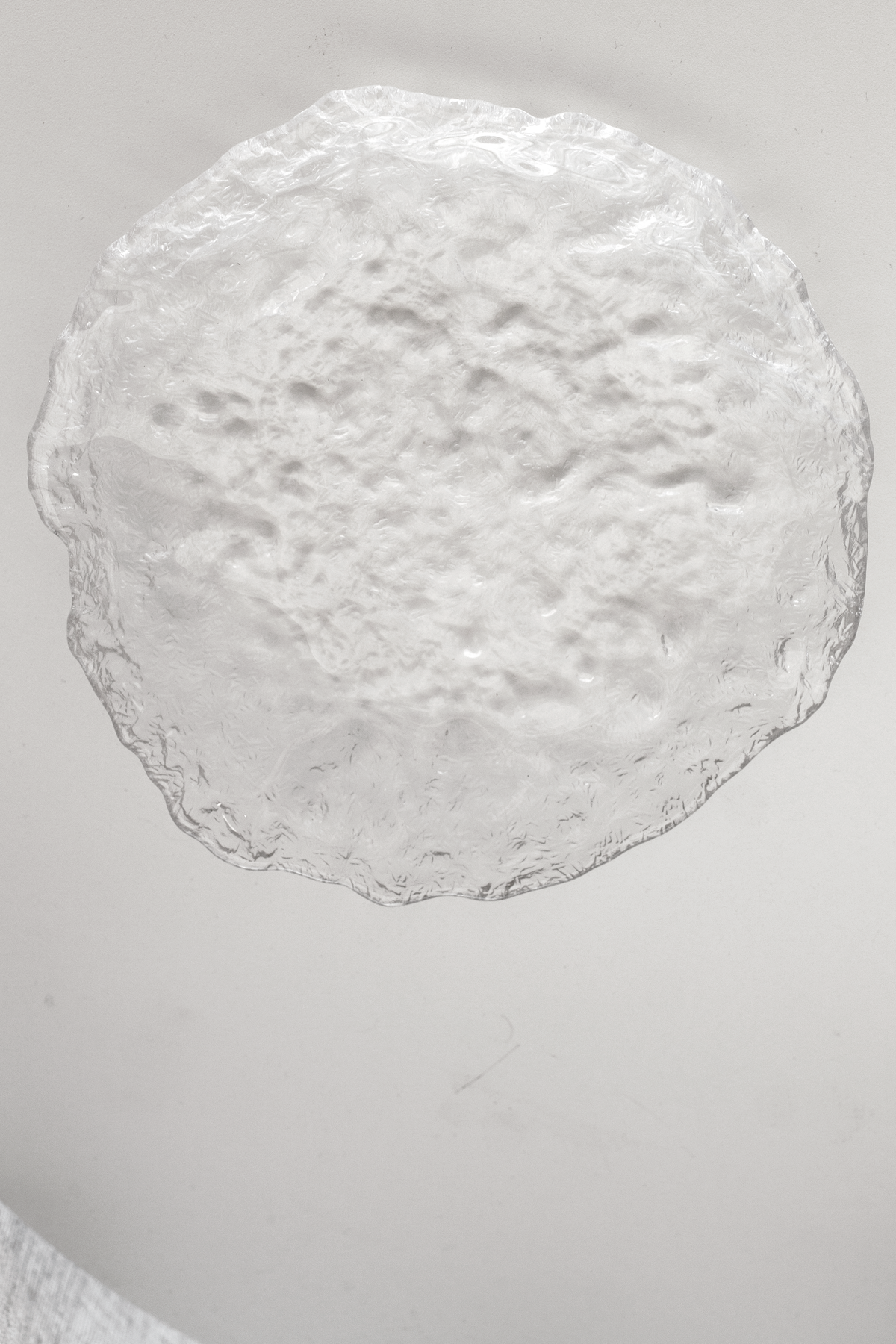 Glacier glass tray on a pale pedestal, close view of the bubbled surface