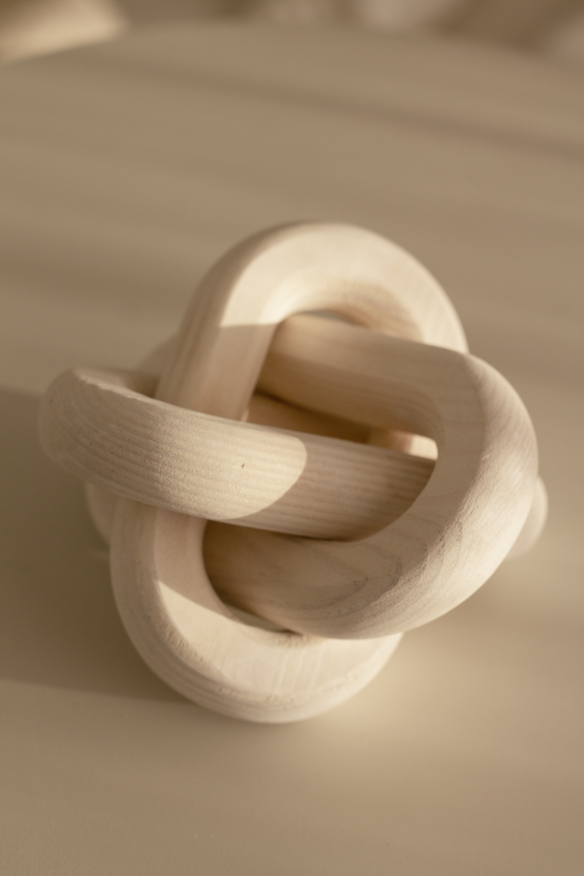 Natural wood knot ornament in warm light, the grain running along each link