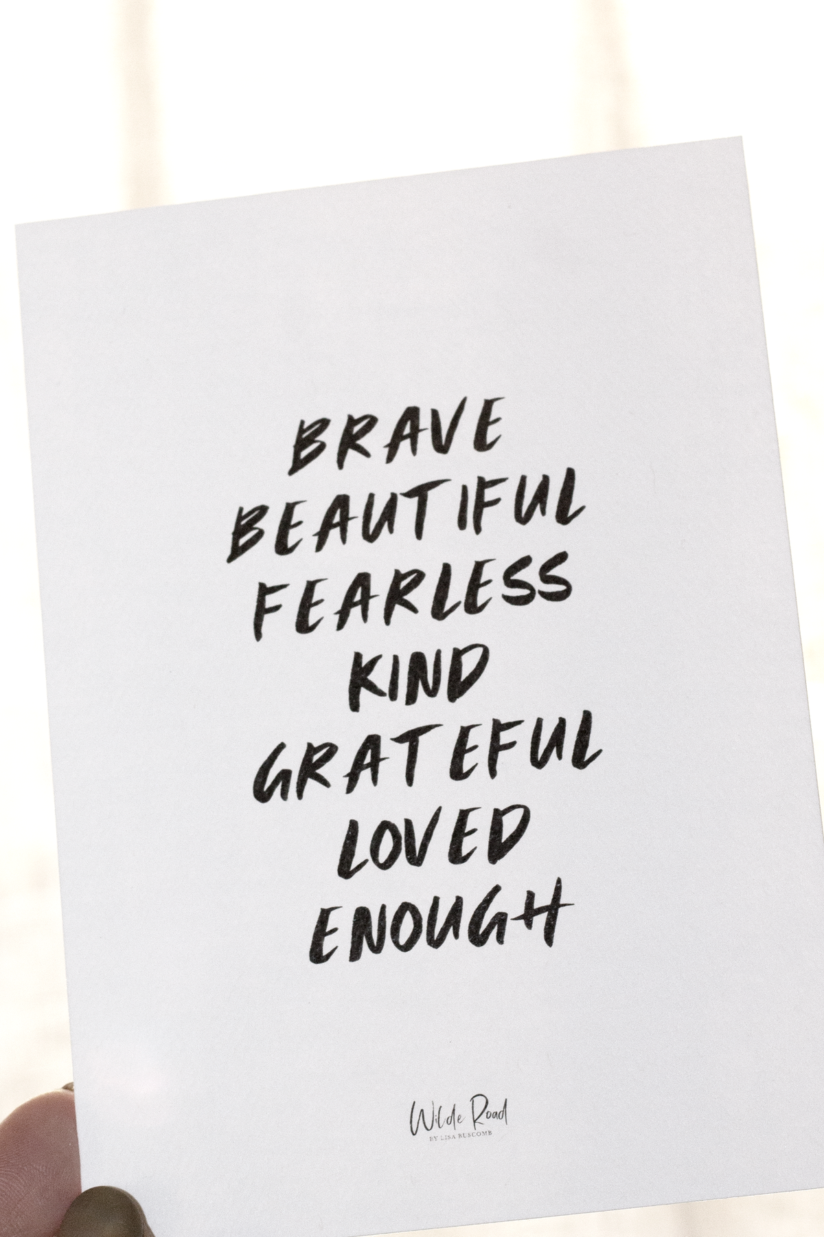 Wilde Road affirmation card on its wooden stand in soft light