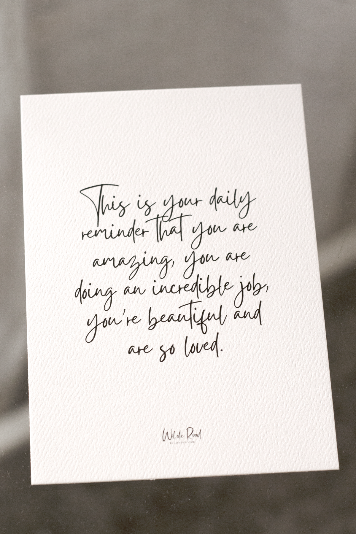 Wilde Road affirmation card standing on a pale bench