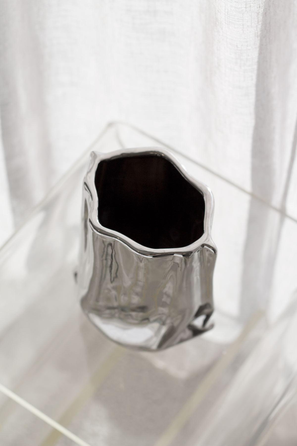 Silver metallic bag vase from above on a clear surface, showing the open top