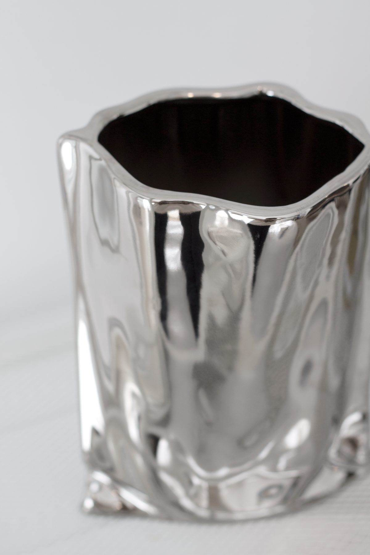 Close view of the silver metallic bag vase rim and mirrored crinkled body
