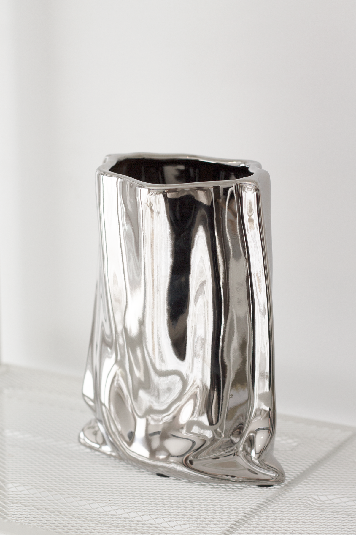 Silver metallic bag vase on white linen with a soft shadow behind