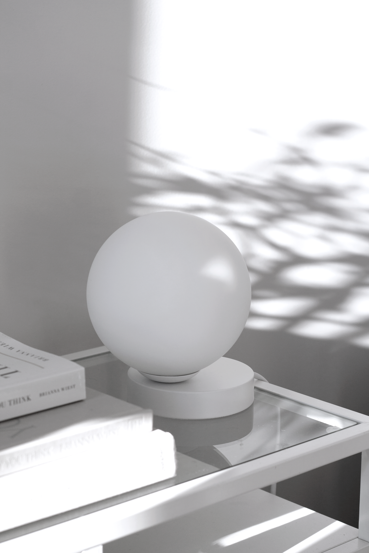 Yuri table lamp casting a warm ambient glow on a console styled with books