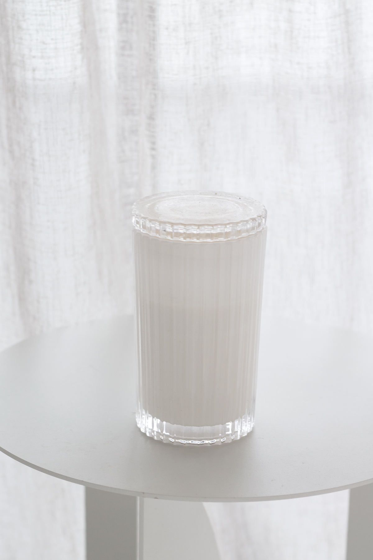 Lit Celebration candle in cut glass on a white surface