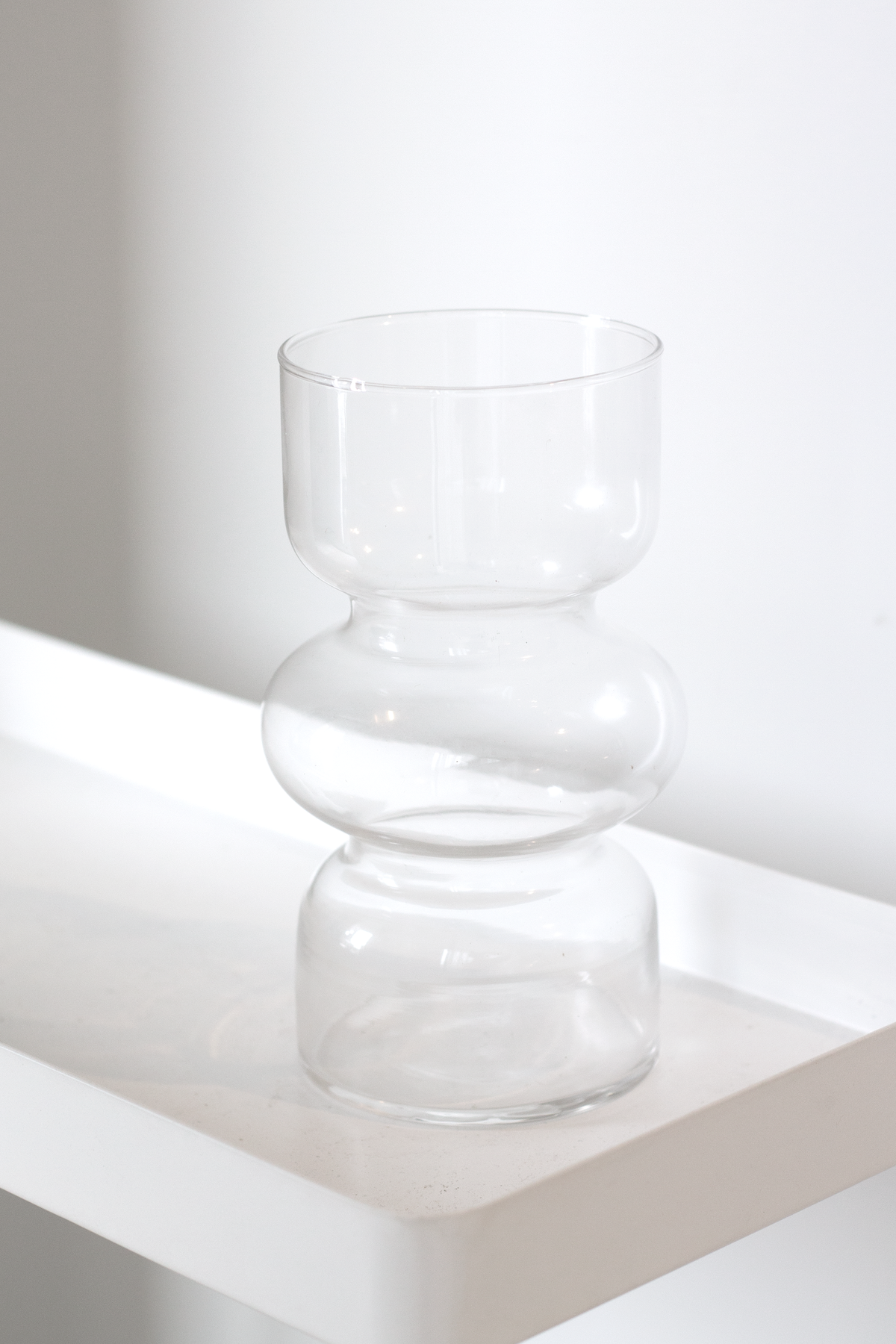 Clear Shea glass vase on a white ledge with light passing through the glass
