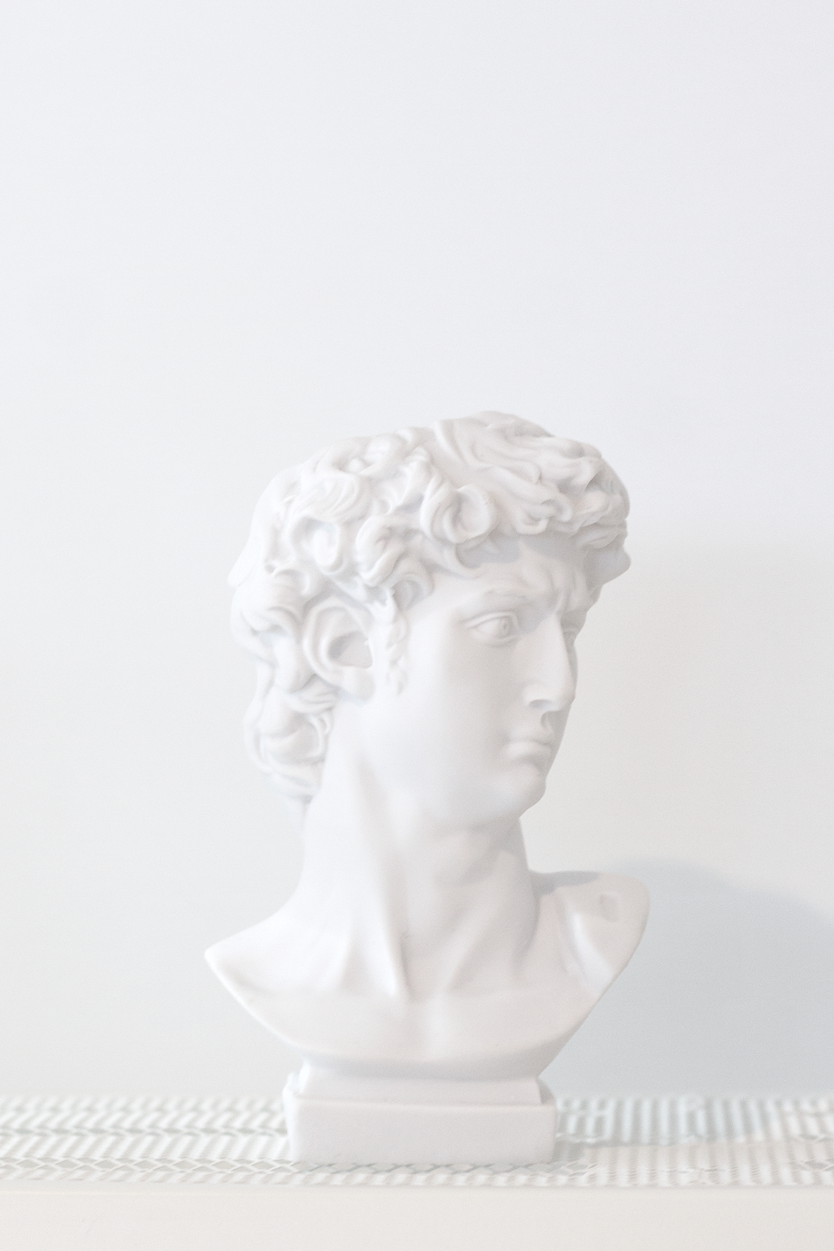 David bust vase on a textured mat against a pale wall, face turned to one side