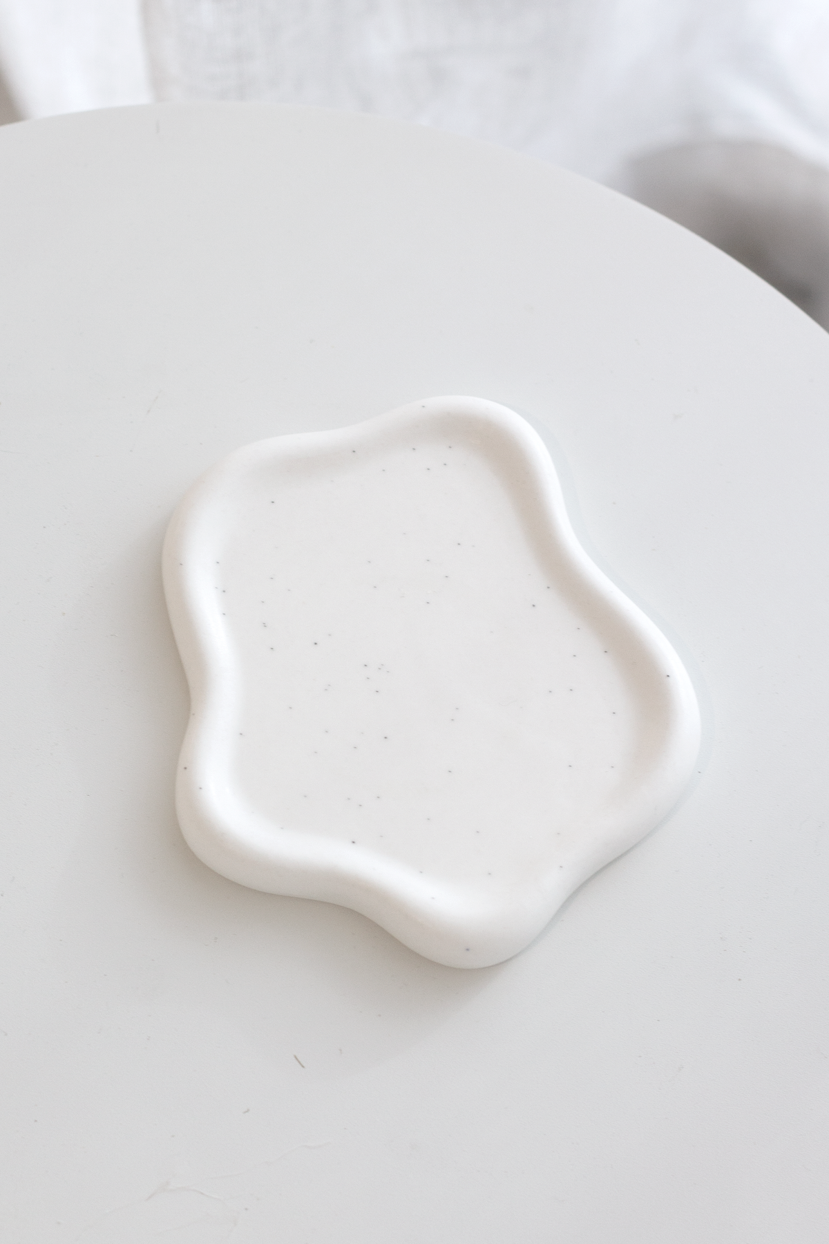 Empty white cloud trinket dish on a round white table