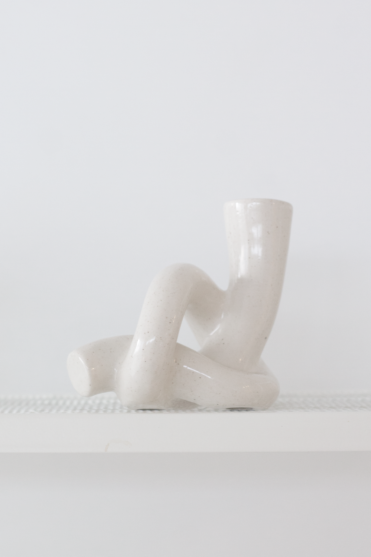 Side profile of the white knot candle holder resting on a pale ledge