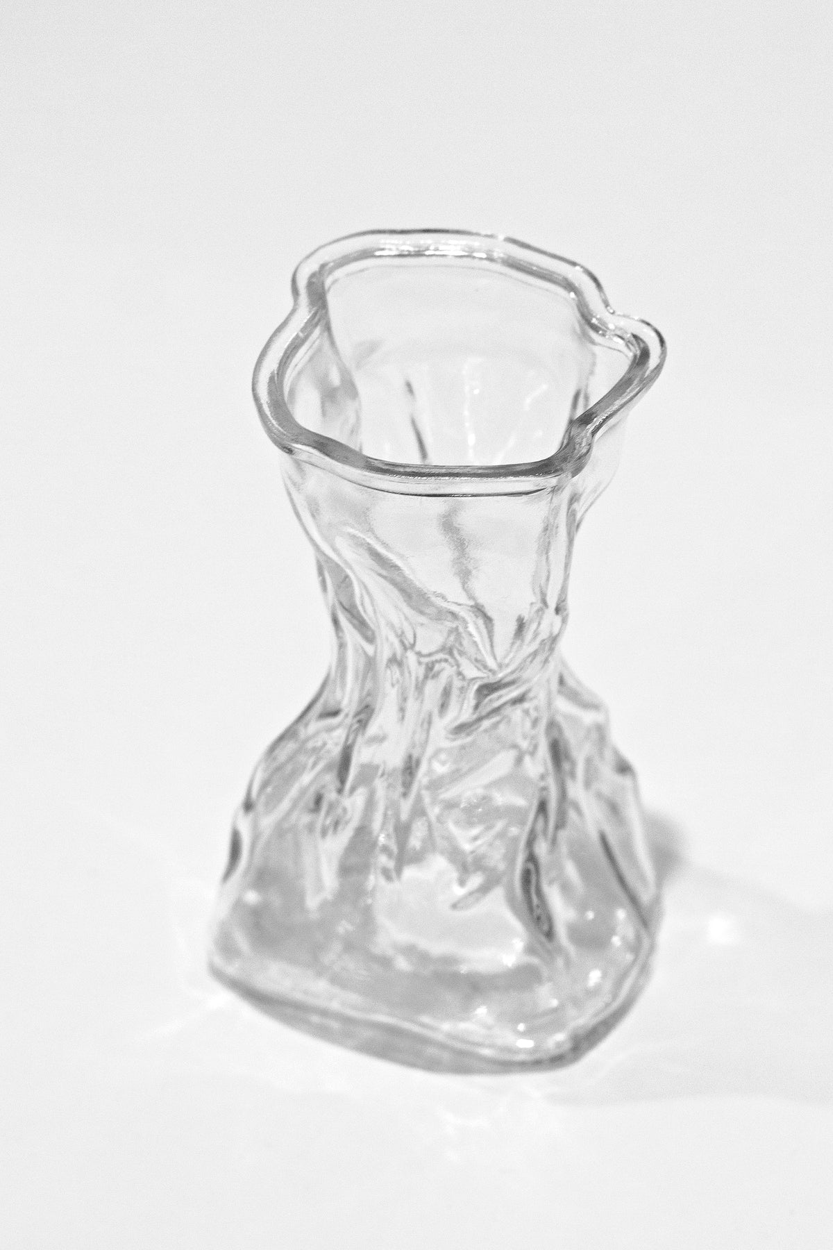 Clear crinkle vase at three quarters on a white surface with a soft cast shadow