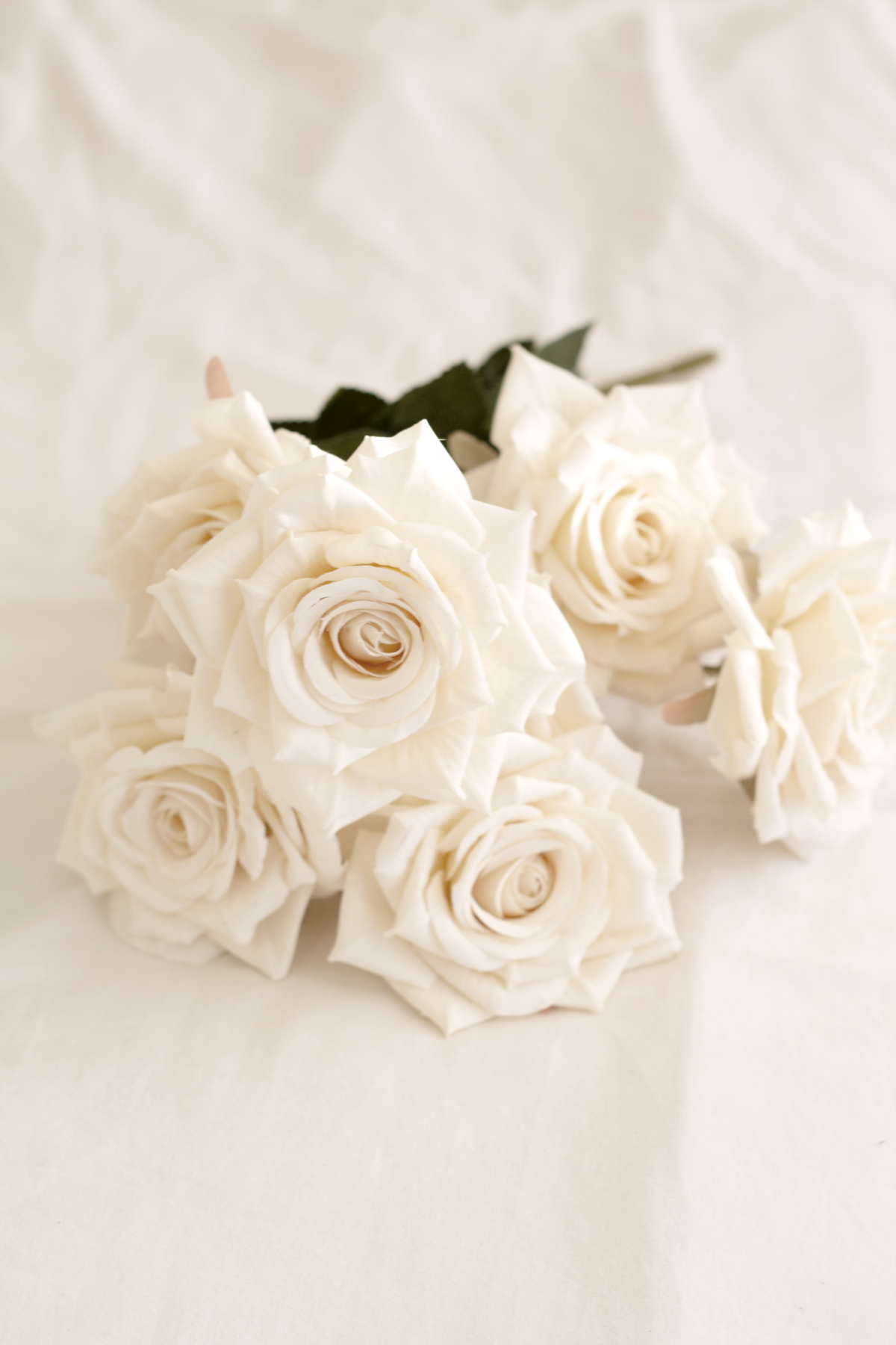 Champagne rose bouquet laid on cream linen, angled view