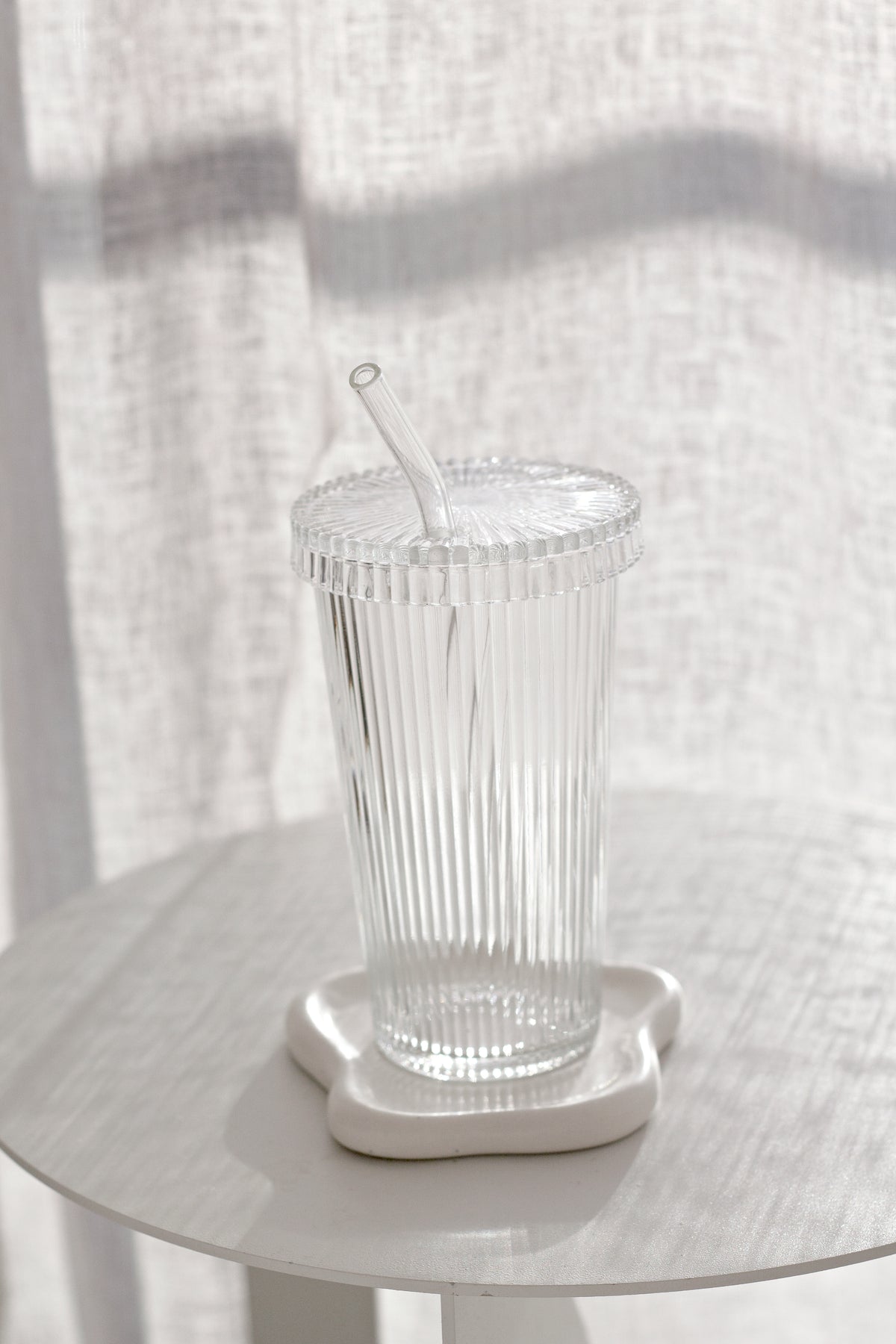 White cloud trinket dish under a ribbed glass tumbler with a straw
