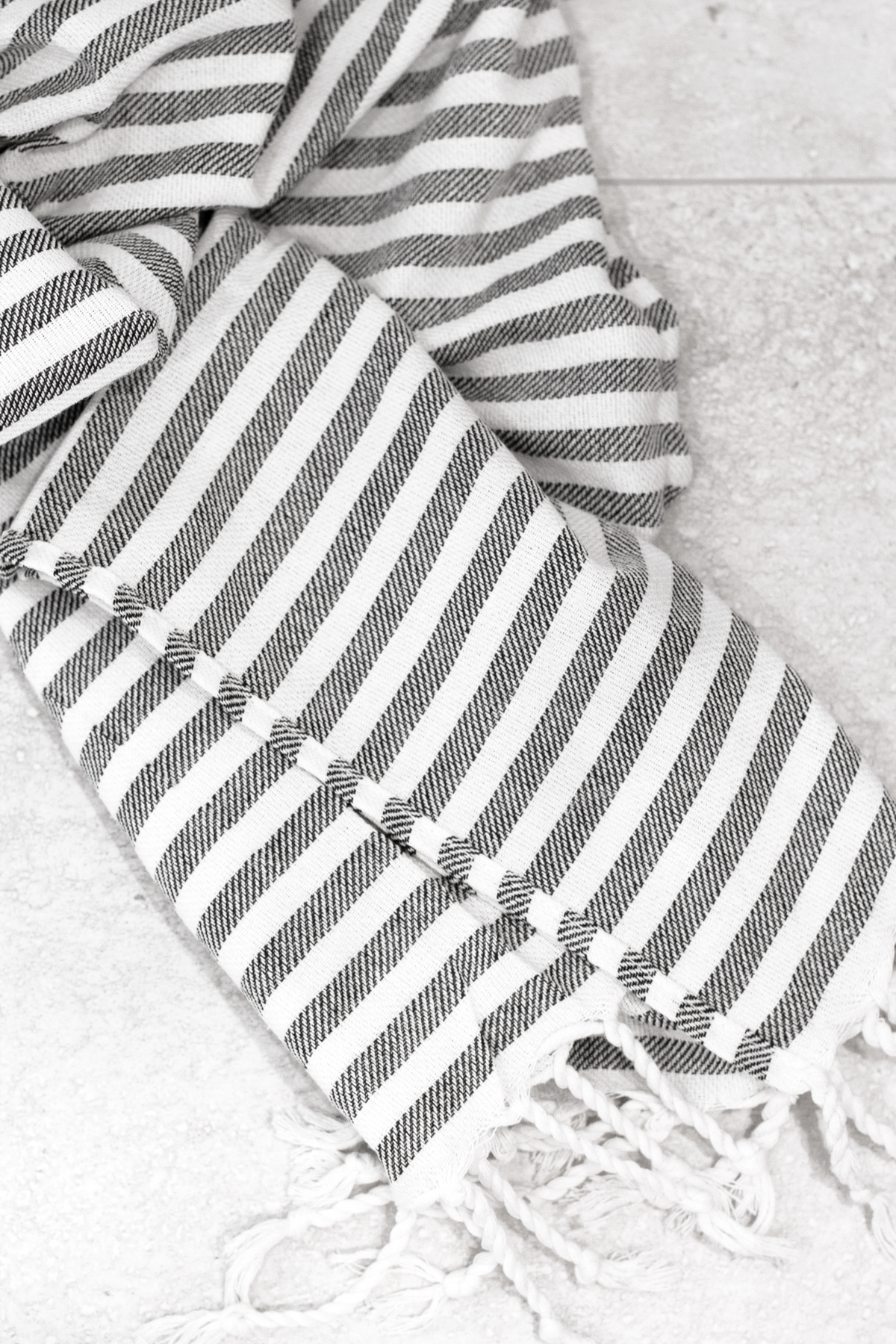 Grey striped Turkish towel folded on a concrete floor