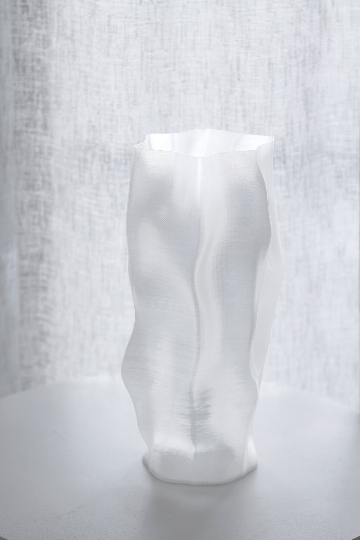 Ripple vase photographed straight on against a textured linen curtain, folds in soft relief