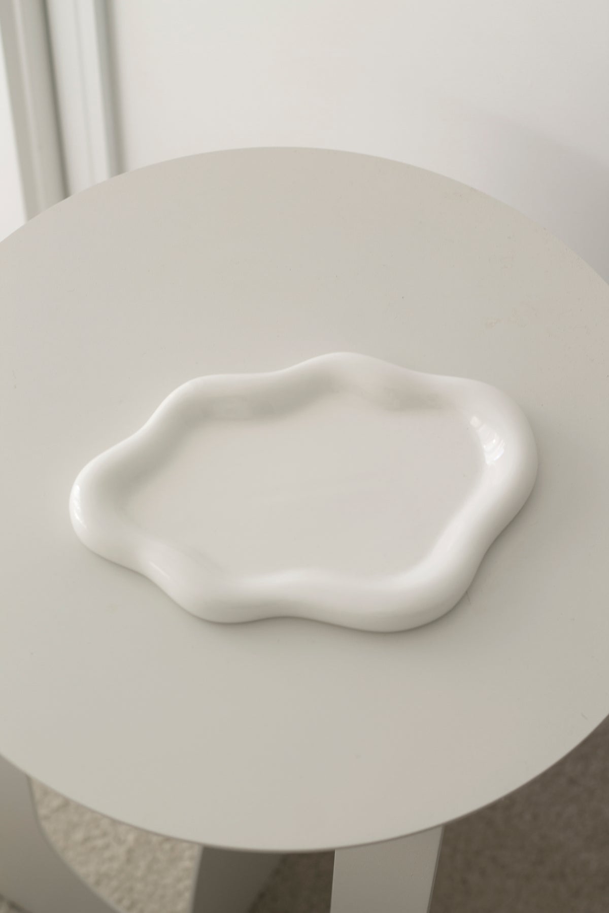 Empty white cloud ceramic tray on a round pale side table