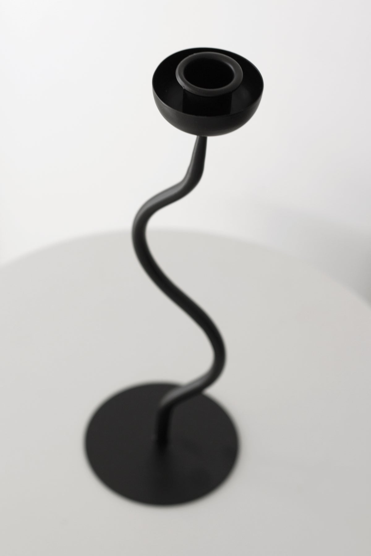 Looking down on the candle holder's cup and the curving stem beneath it