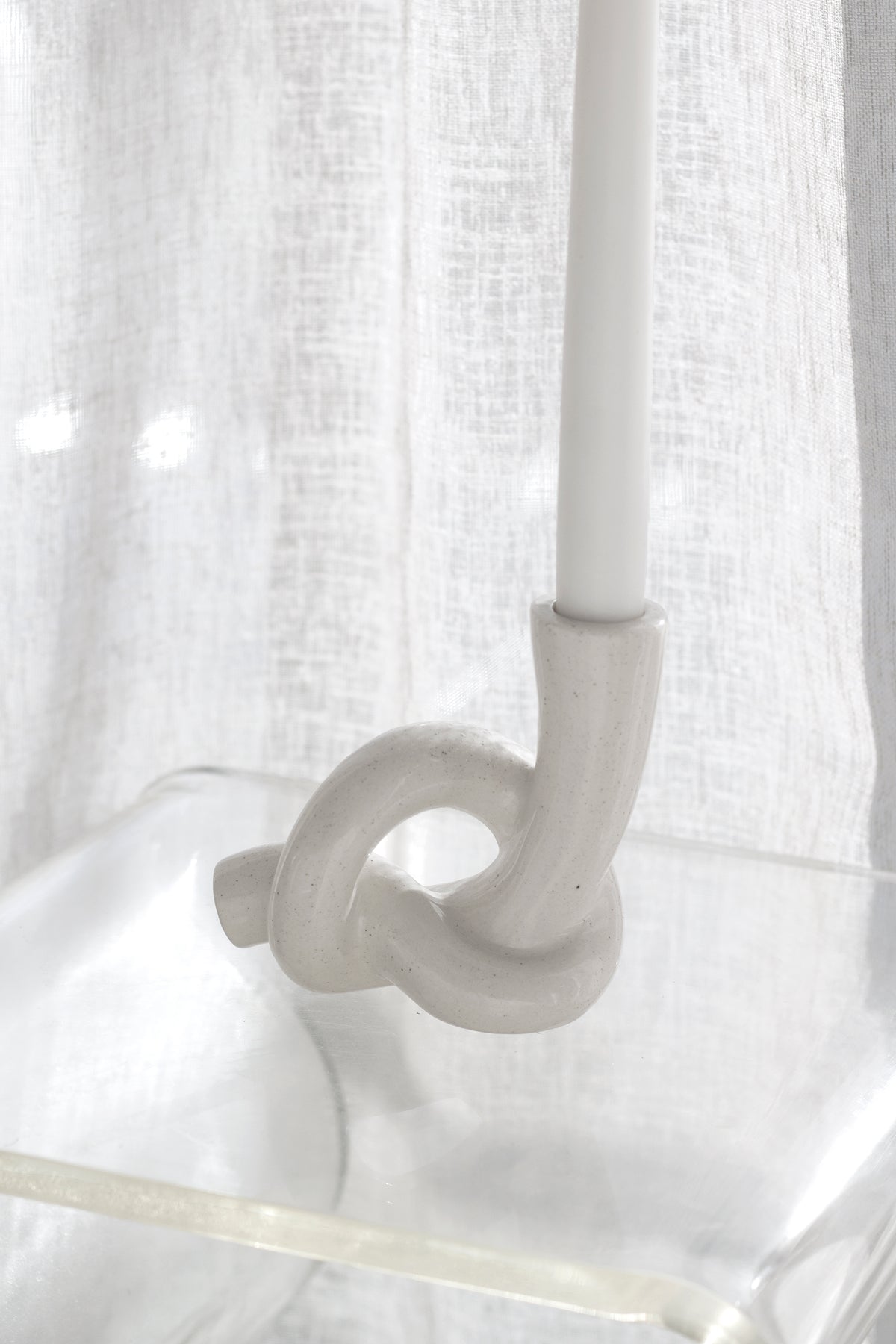 Close crop of the knot holder and candle base on a clear acrylic tabletop