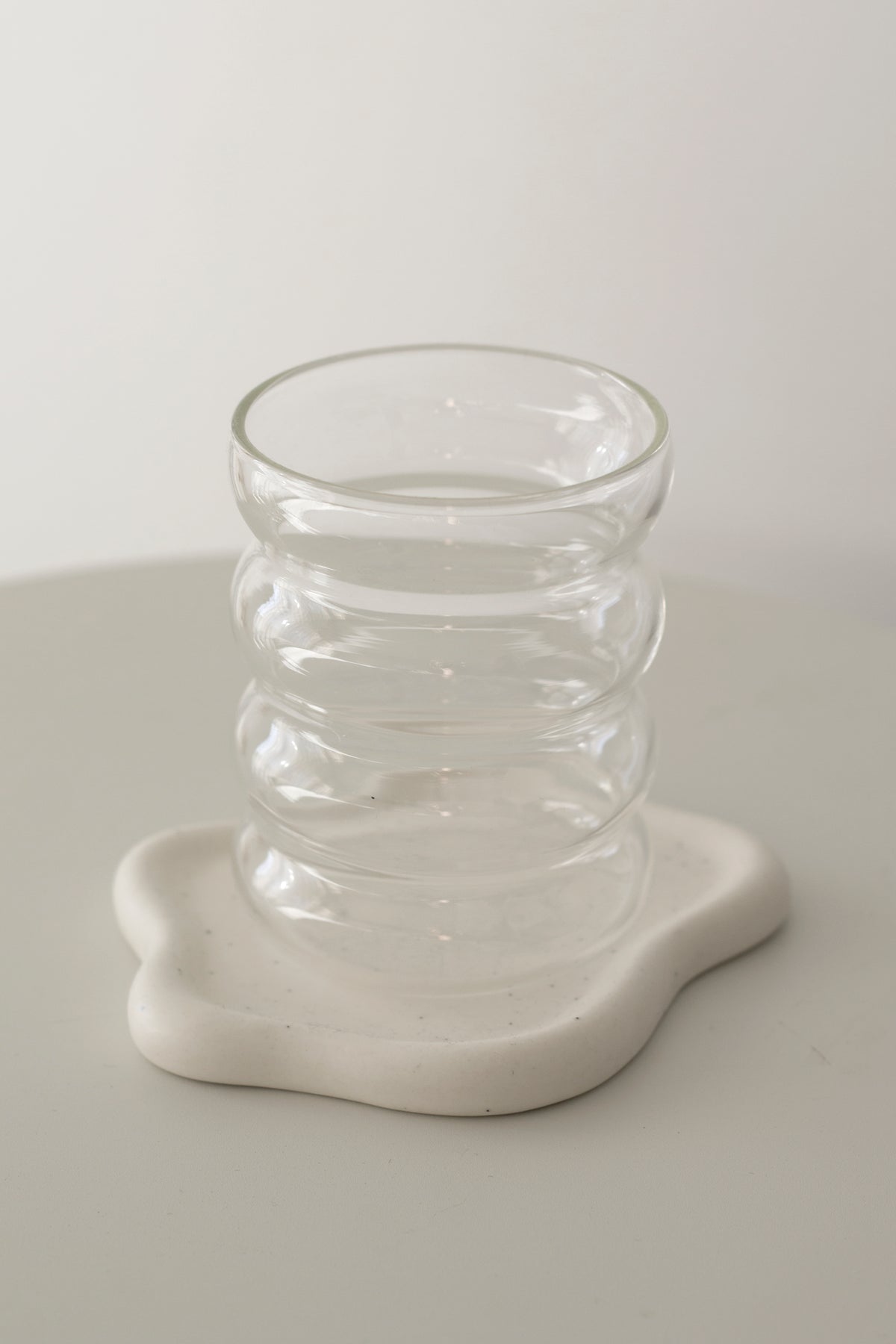 Caterpillar rippled glass tumbler standing on a white wavy coaster
