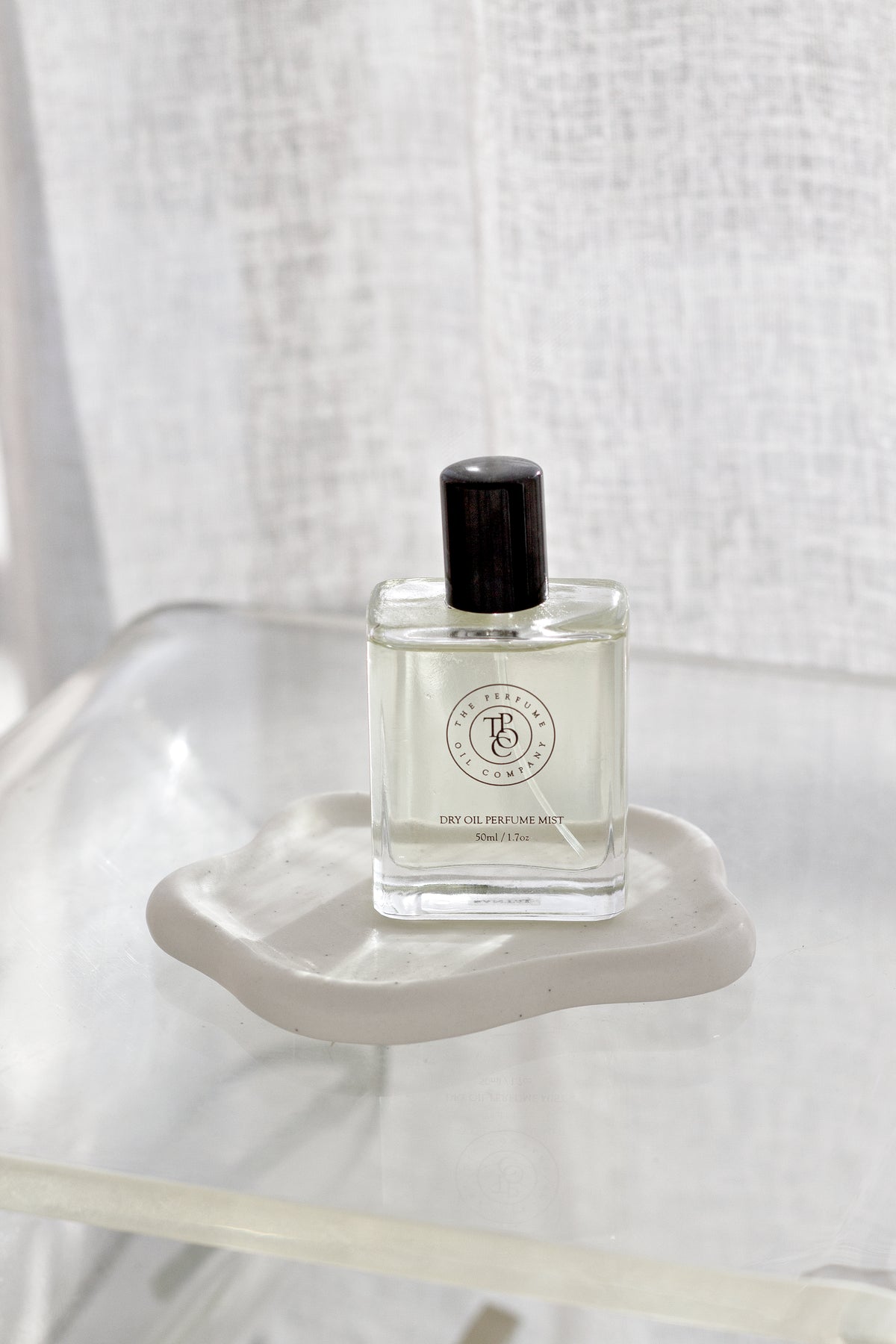 White cloud trinket dish with a perfume bottle against a sheer linen backdrop