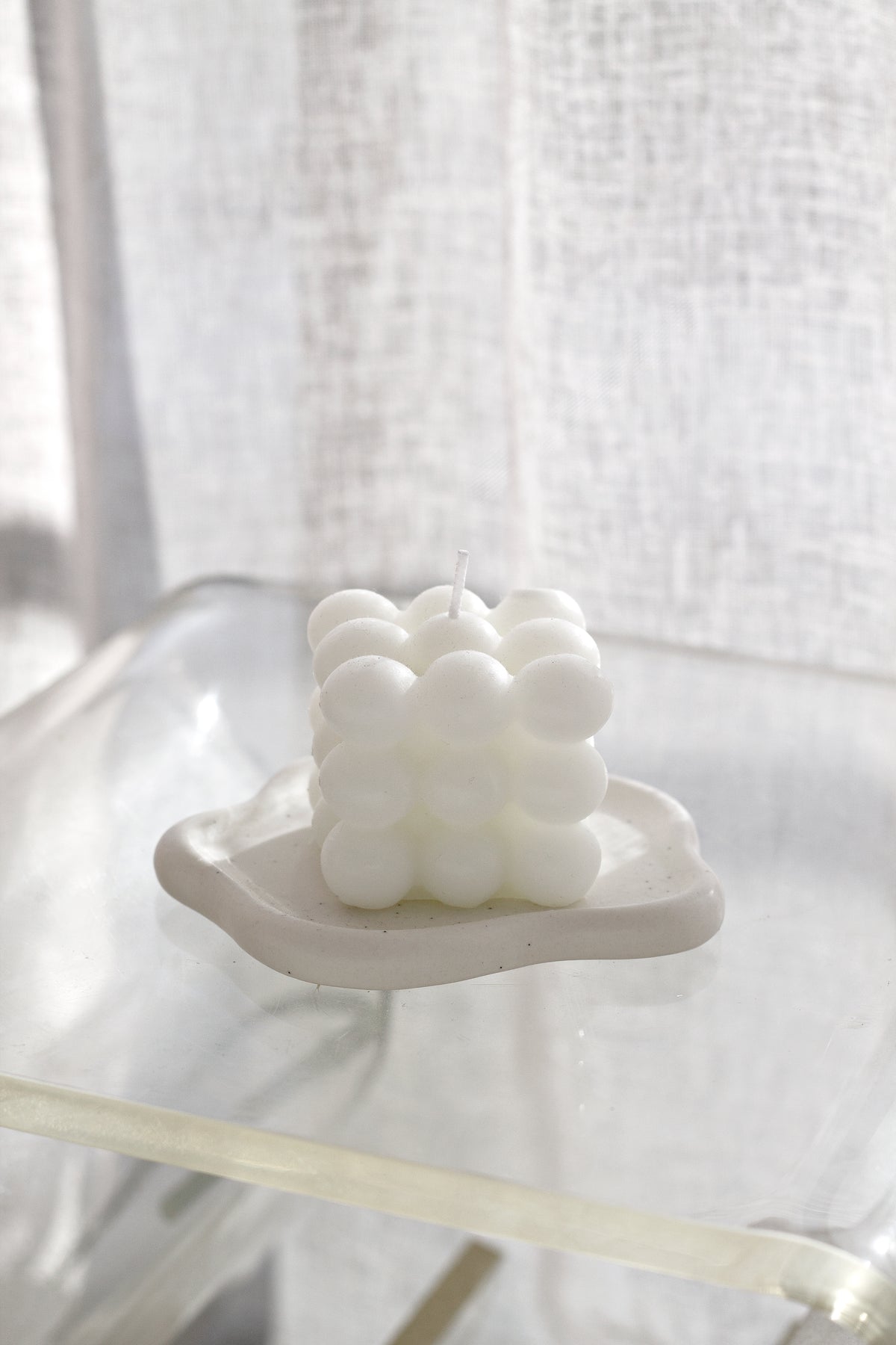 White cloud trinket dish holding a bubble candle on a glass table