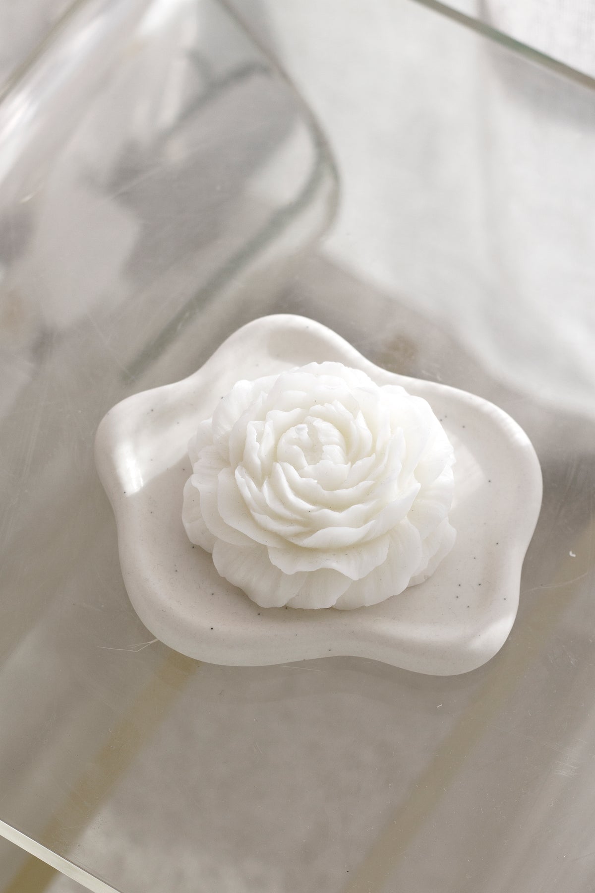 White cloud trinket dish holding a rose shaped candle, seen from above