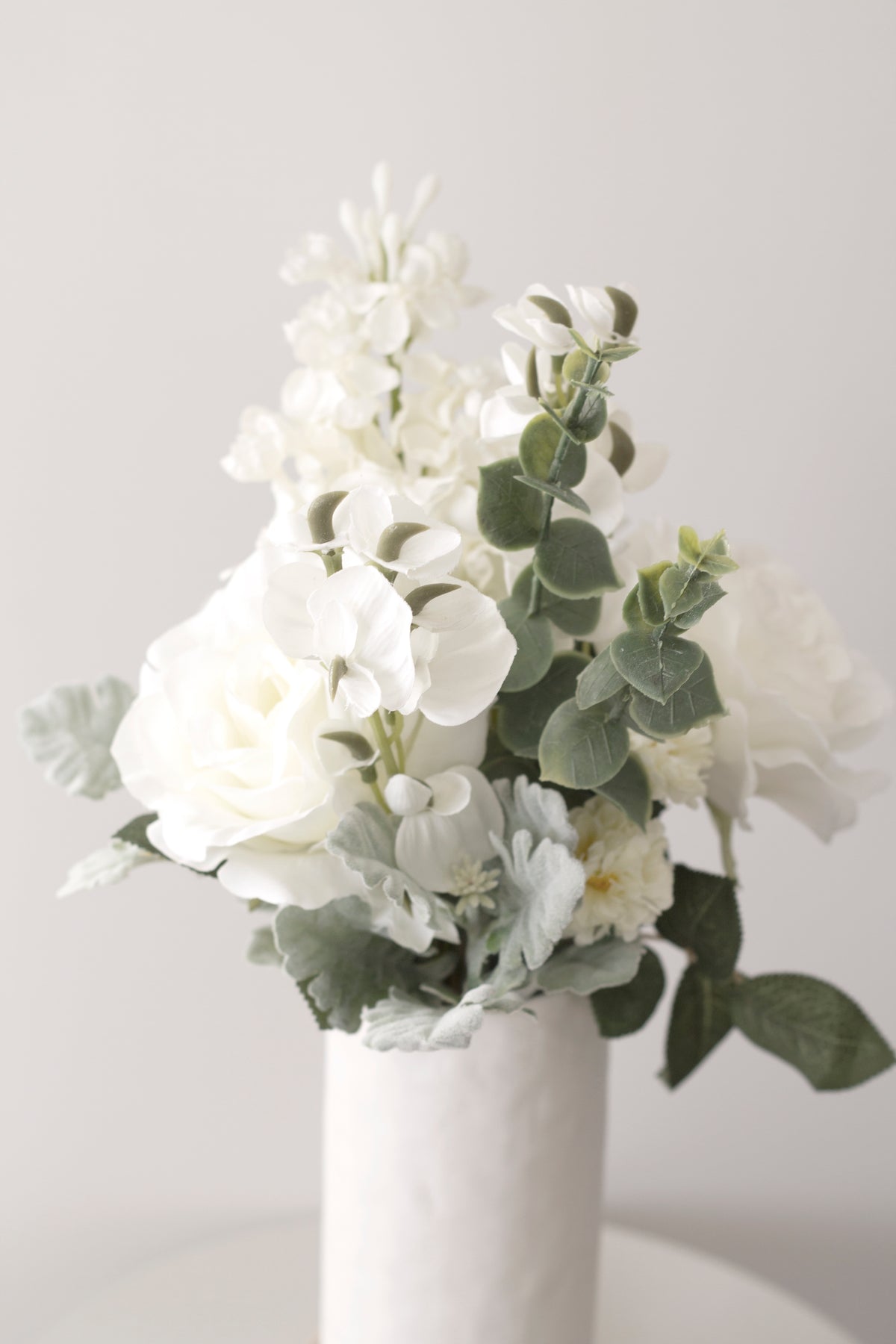 White faux bouquet with eucalyptus in a white vase