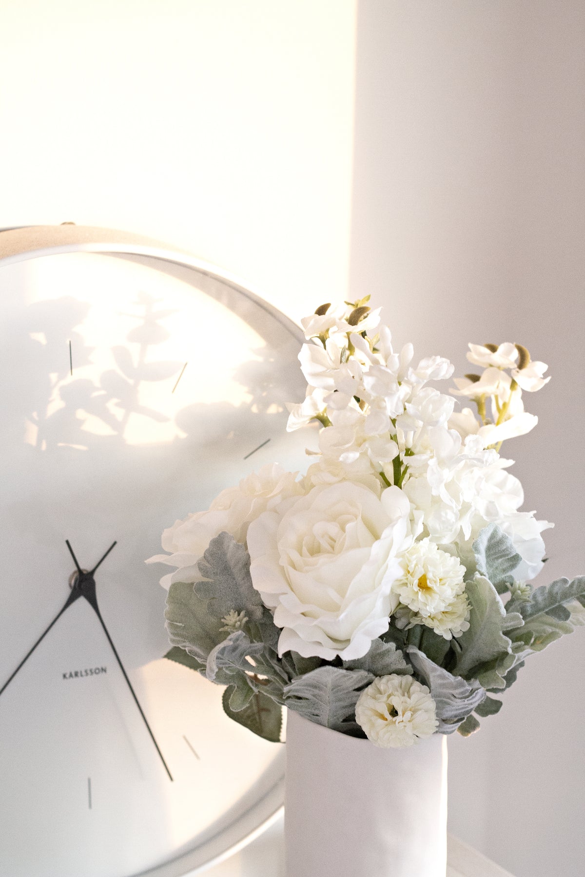White faux bouquet beside a round wall mirror