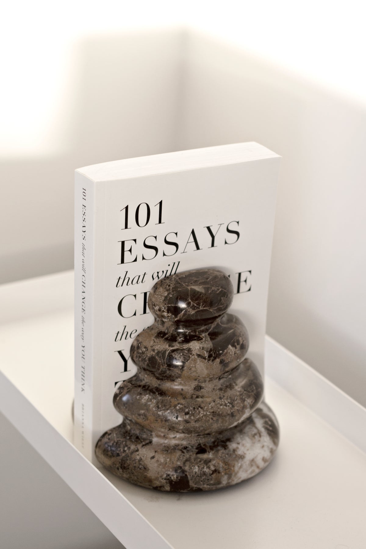 Casa bookend holding a book on a white shelf