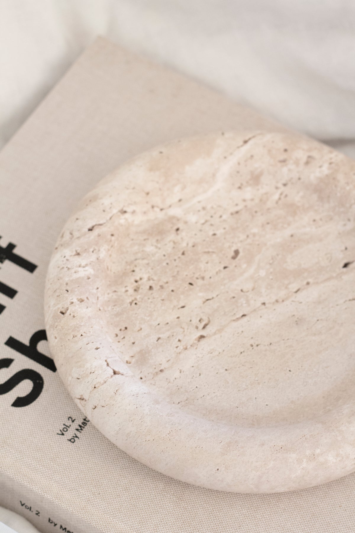 Close-up of the Bay Round Tray on a linen-covered book