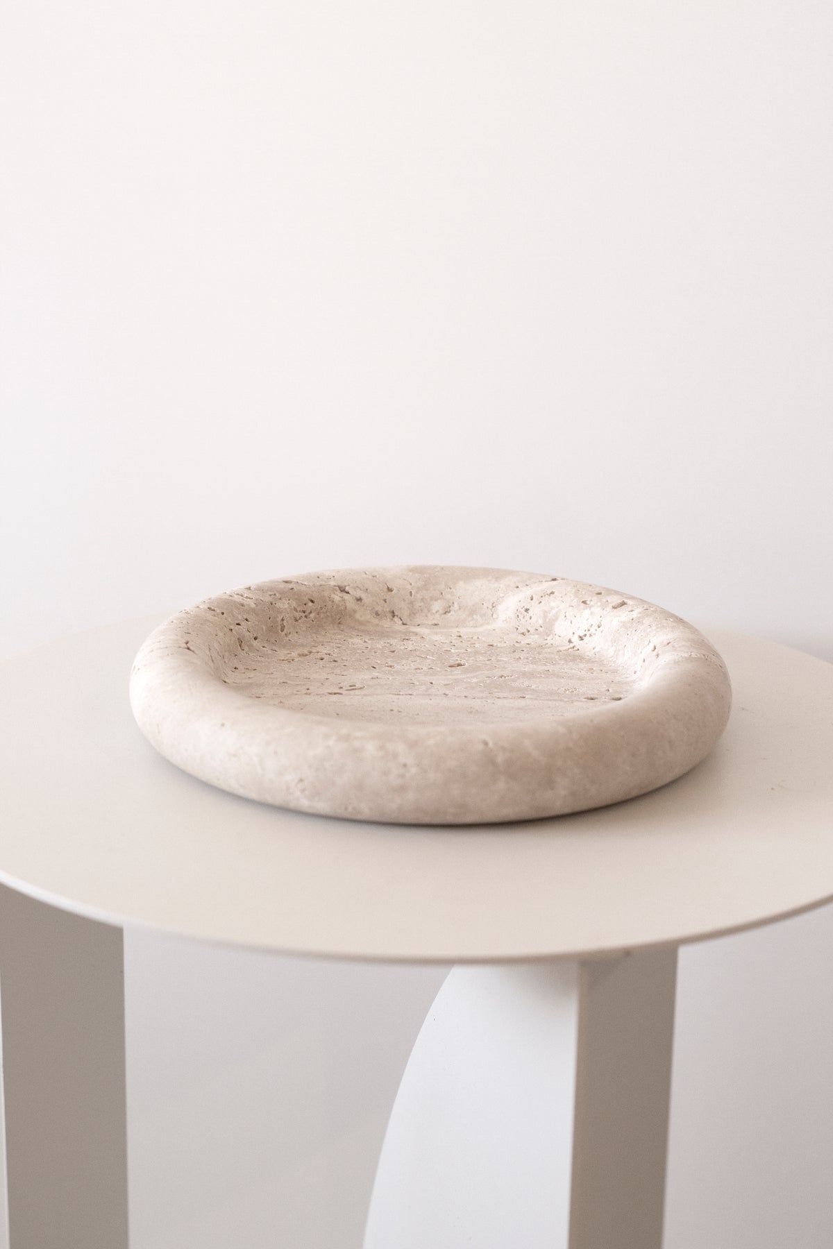 Bay Round Tray on a white side table, low side view of its soft rolled edge