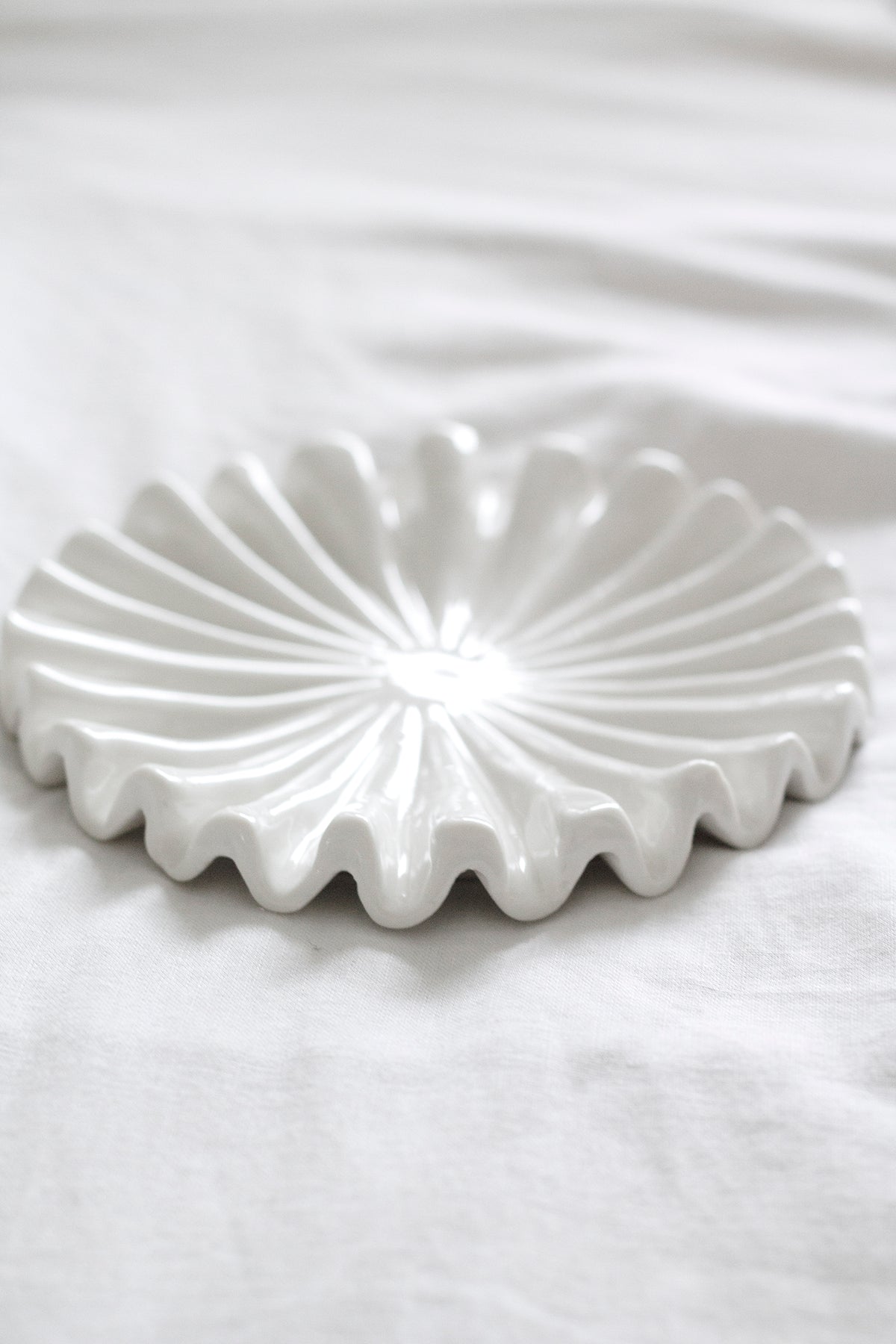 Empty white ruffle ceramic tray on soft white bedding