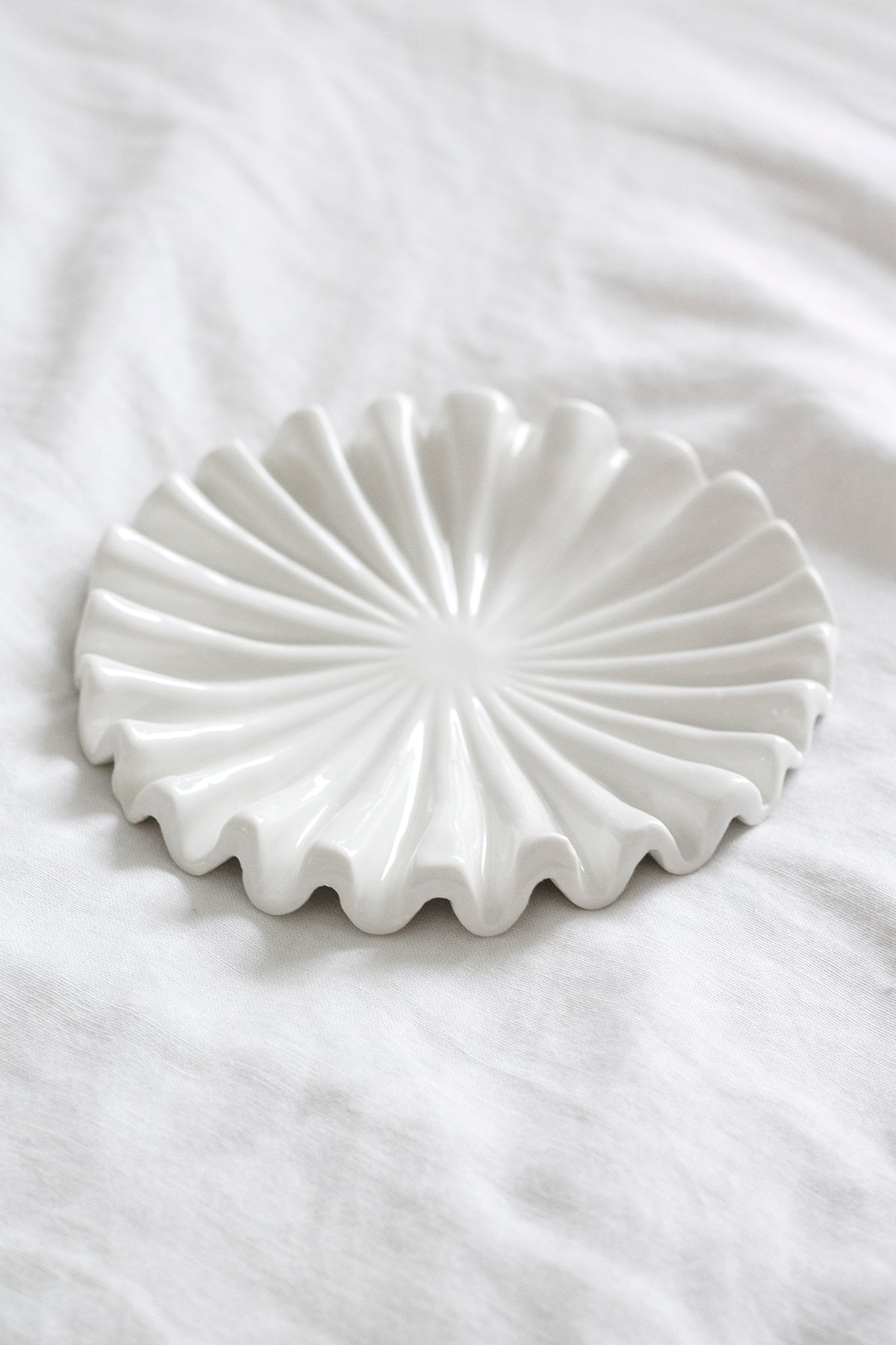 Close view of the white tray's rippled, fluted rim on white linen