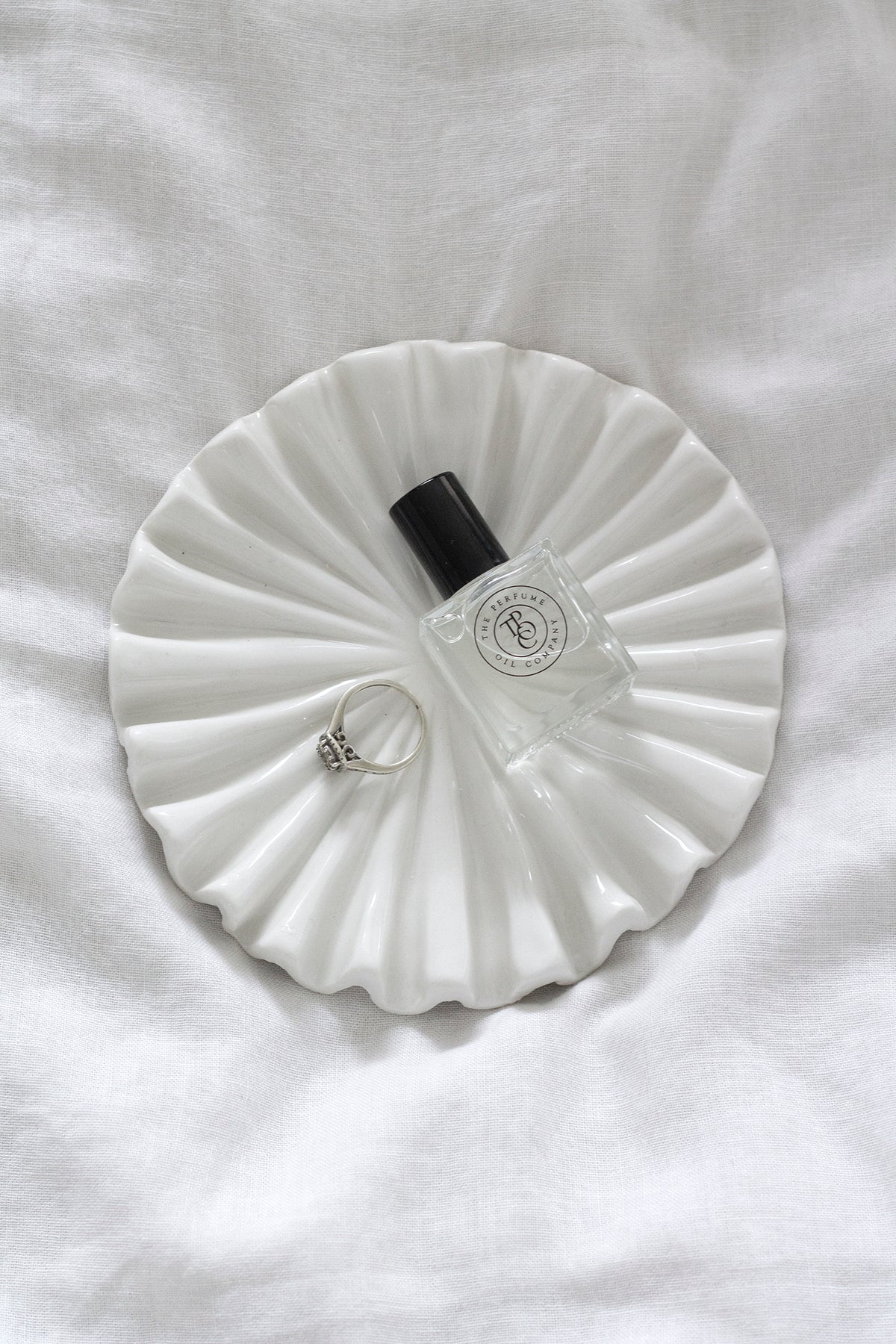 Small bottle resting on the white ruffle tray on crumpled linen