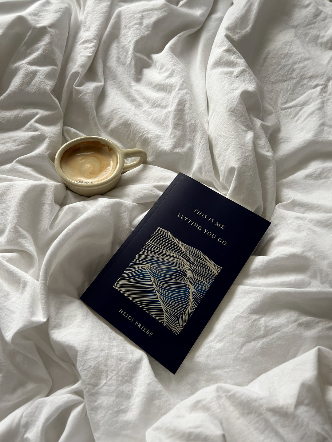 This Is Me Letting You Go with a cup of coffee on white bedding