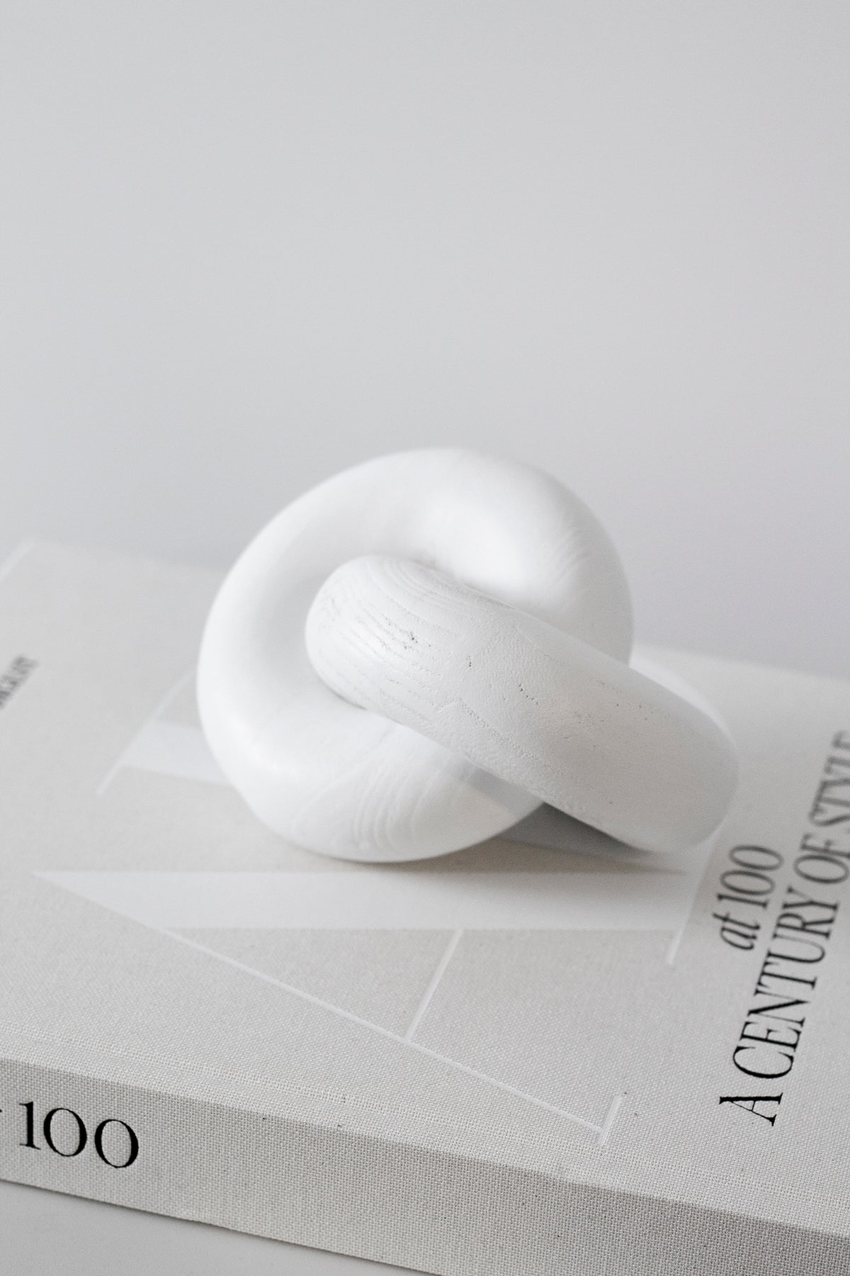 White wooden knot sculpture on a stack of white hardback books