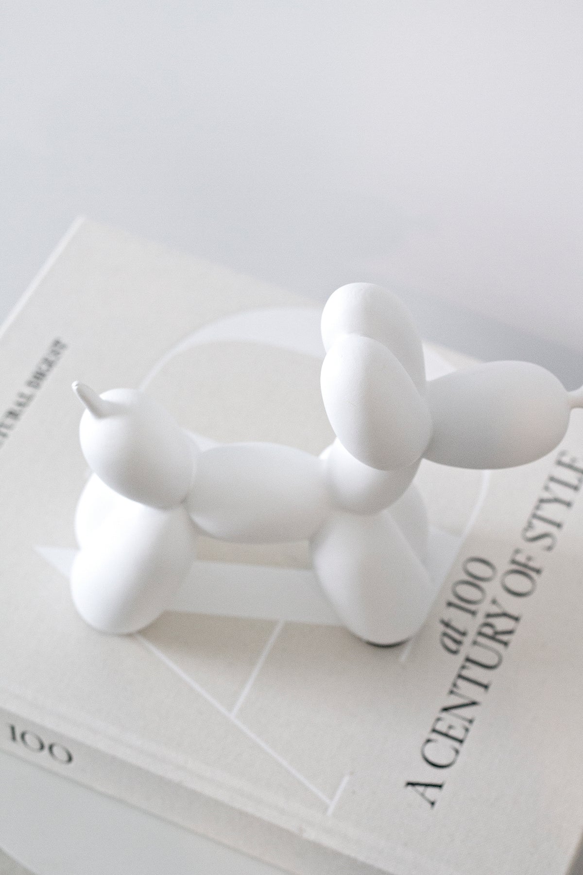 White ceramic balloon dog sculpture, close view on a coffee table book