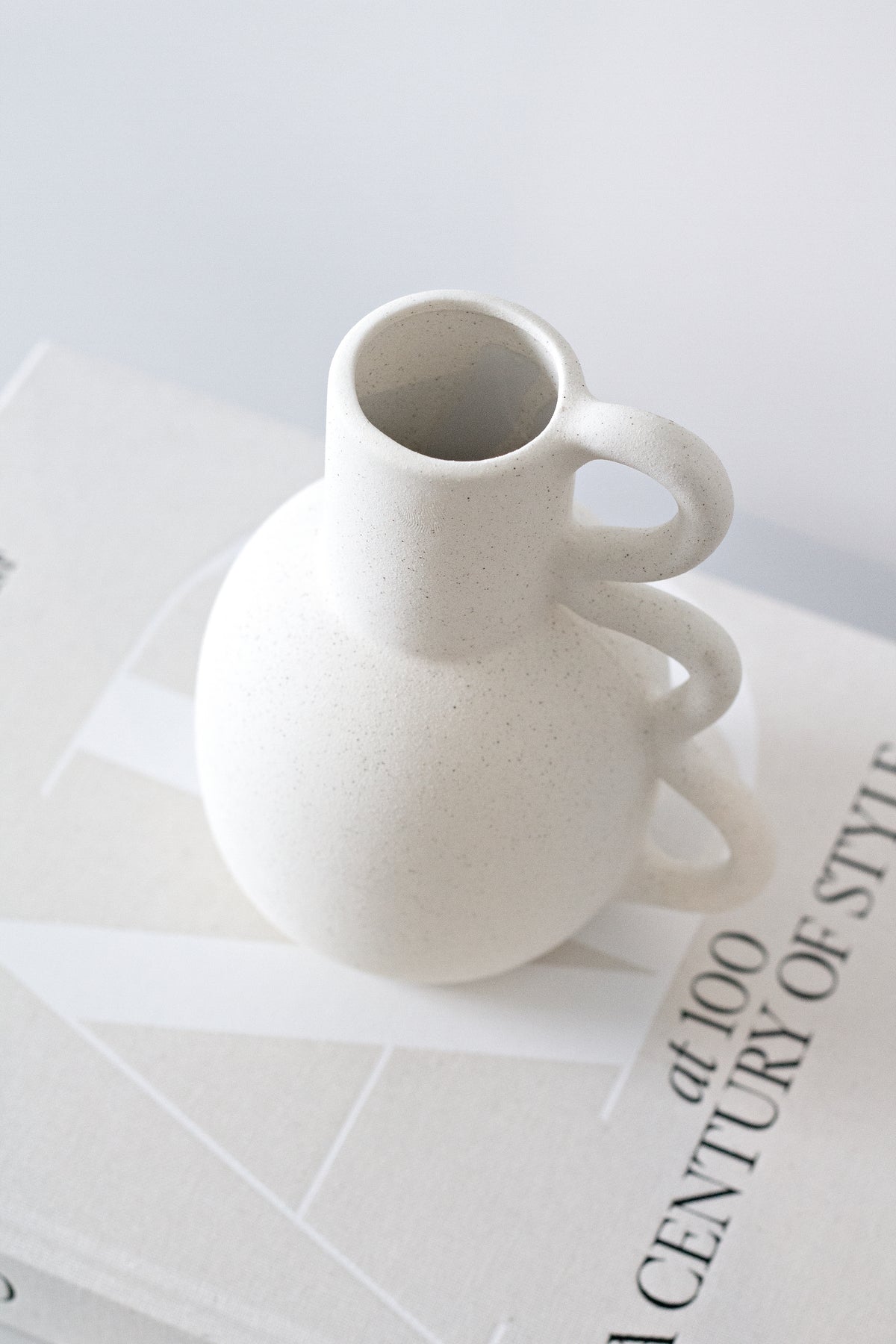 Chloe vase standing on a stack of books on a white surface