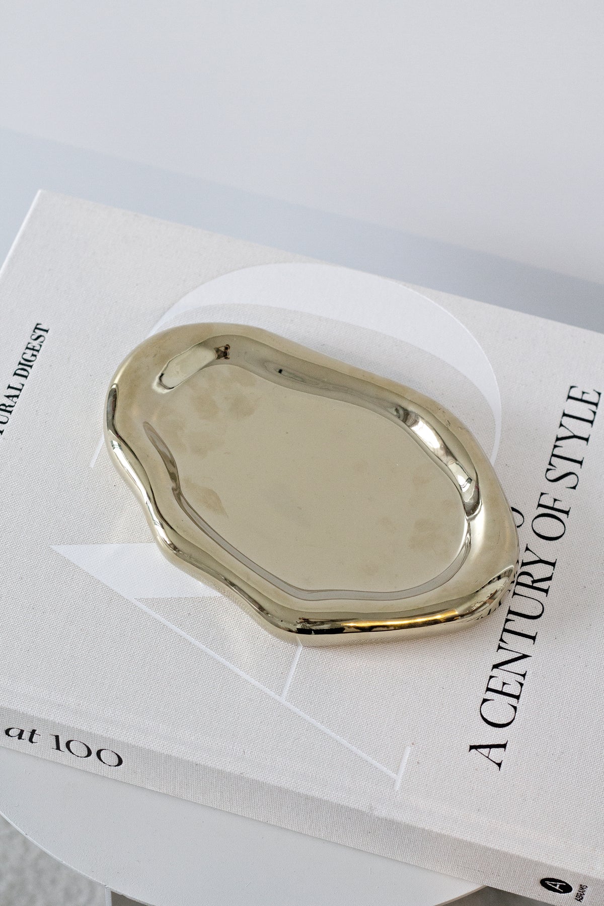 Gold cloud tray resting on a stack of white books on a pale table