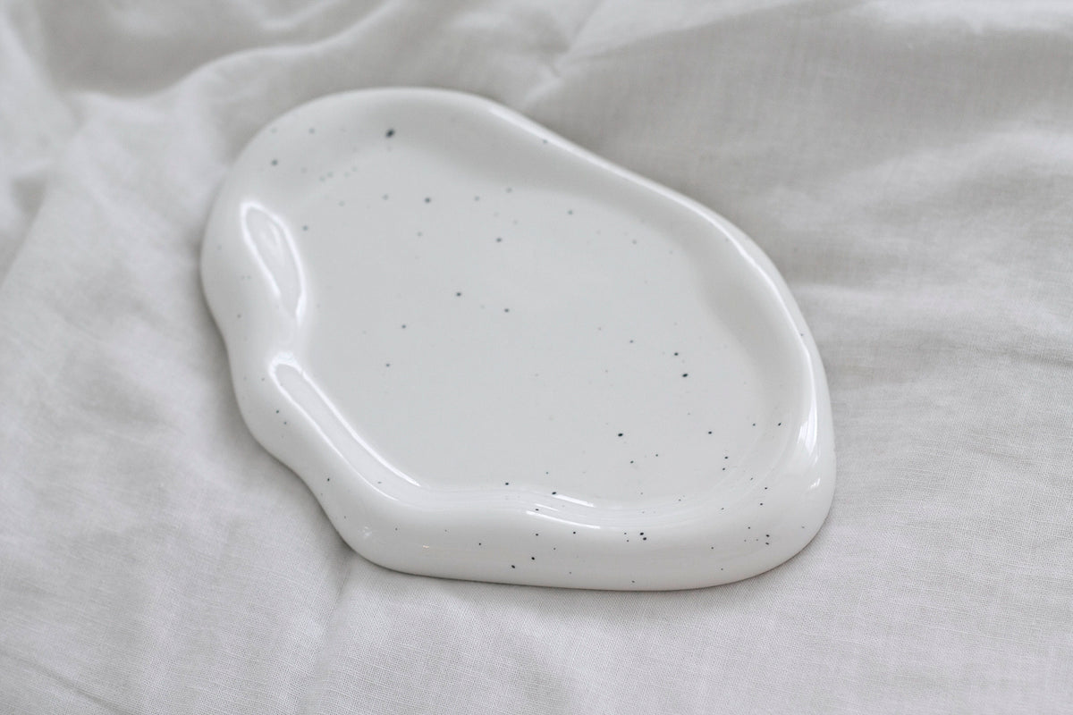 Empty speckled white cloud ceramic tray resting on white linen