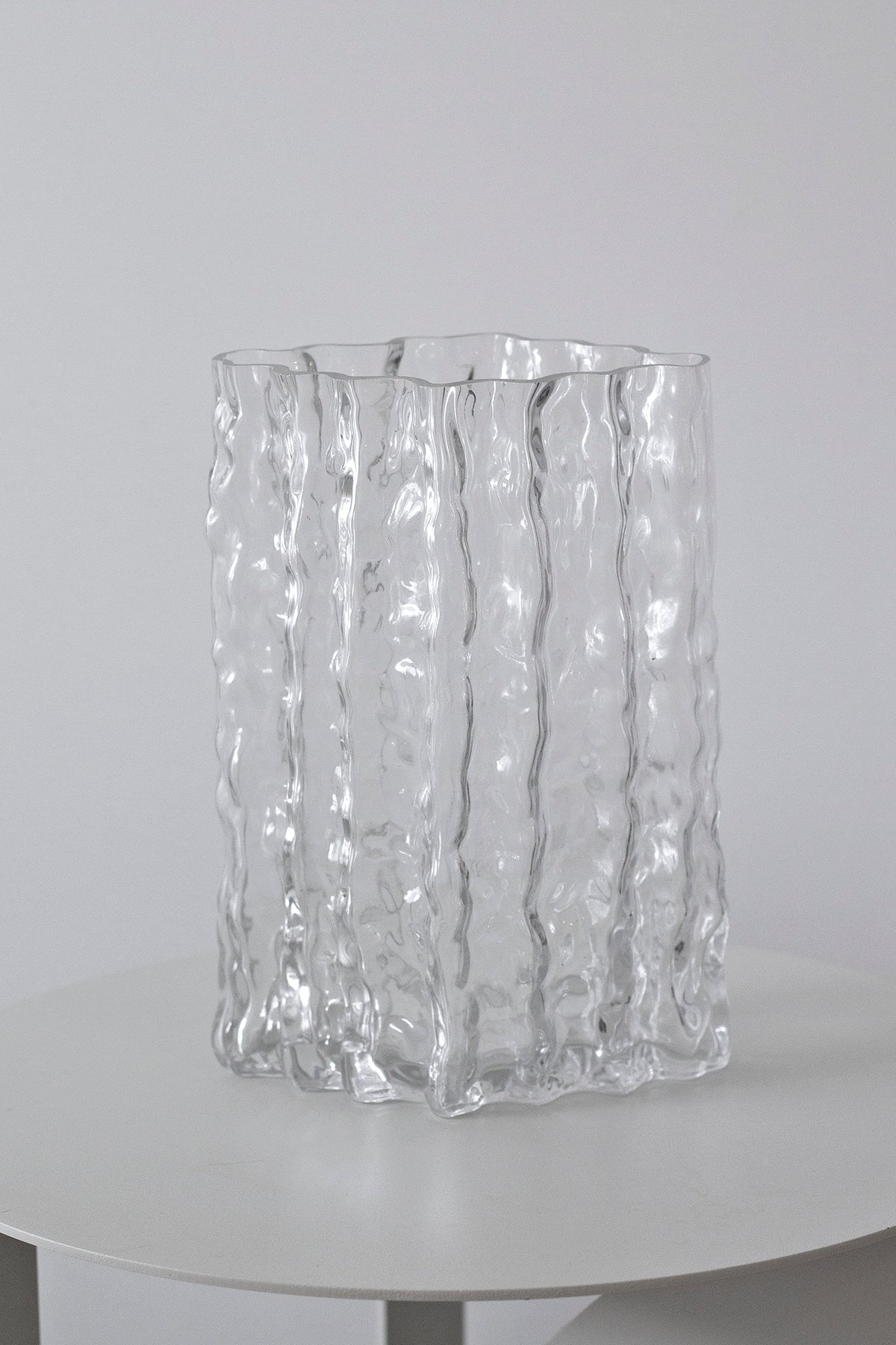 Clear Glacier vase centred on a round white pedestal against a pale wall