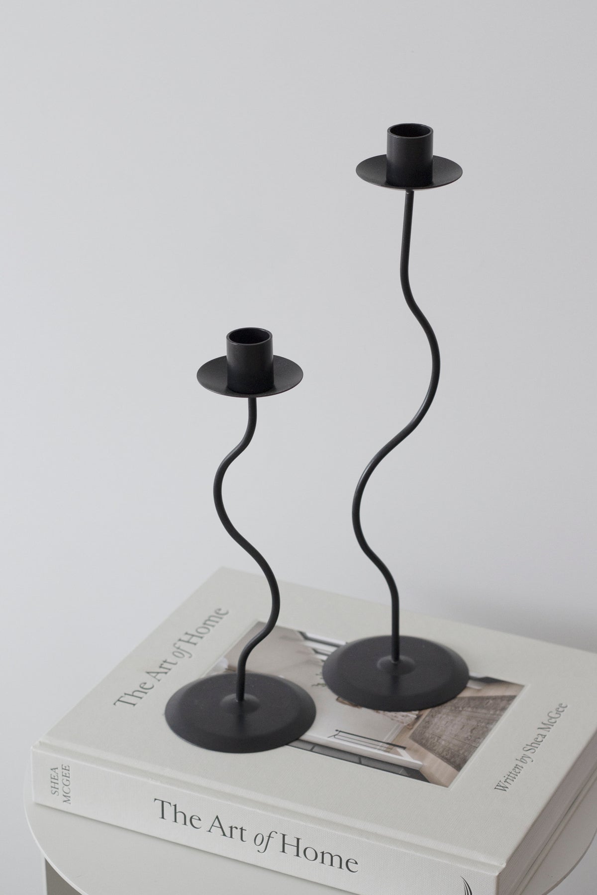 Black Hera pair empty on stacked books, photographed low against a soft grey background