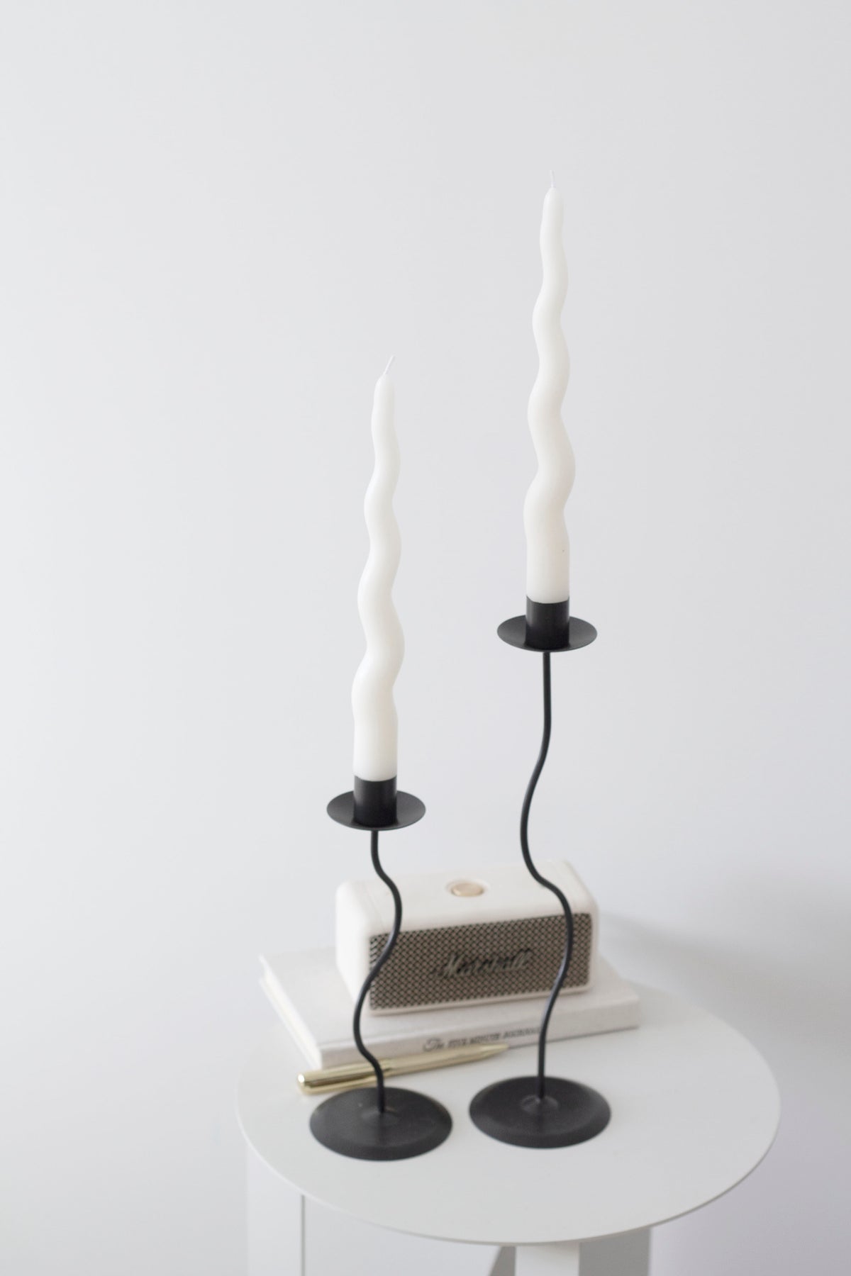 Black Hera holders with cream twisted tapers on a small round white side table