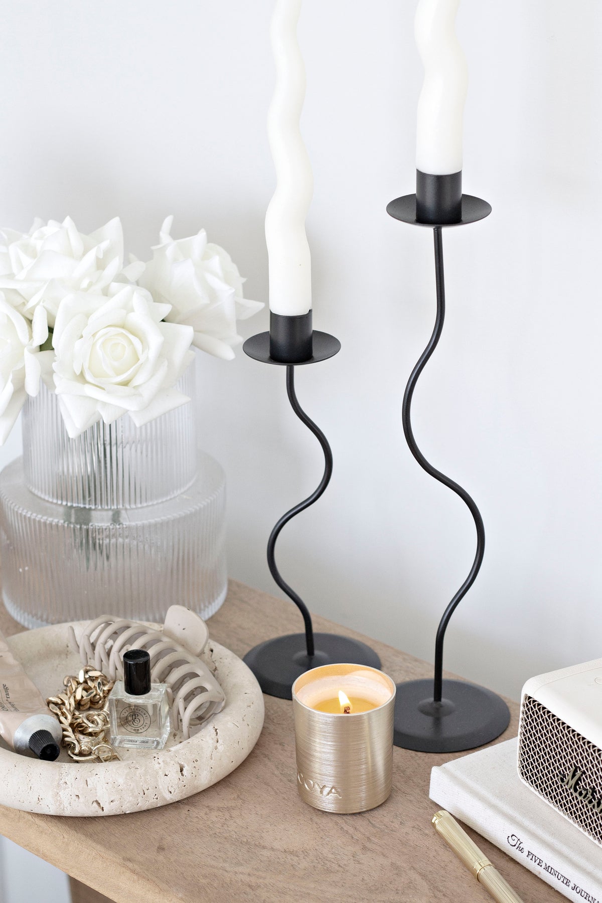 Black Hera pair with cream tapers on a timber shelf with white roses and a lit candle