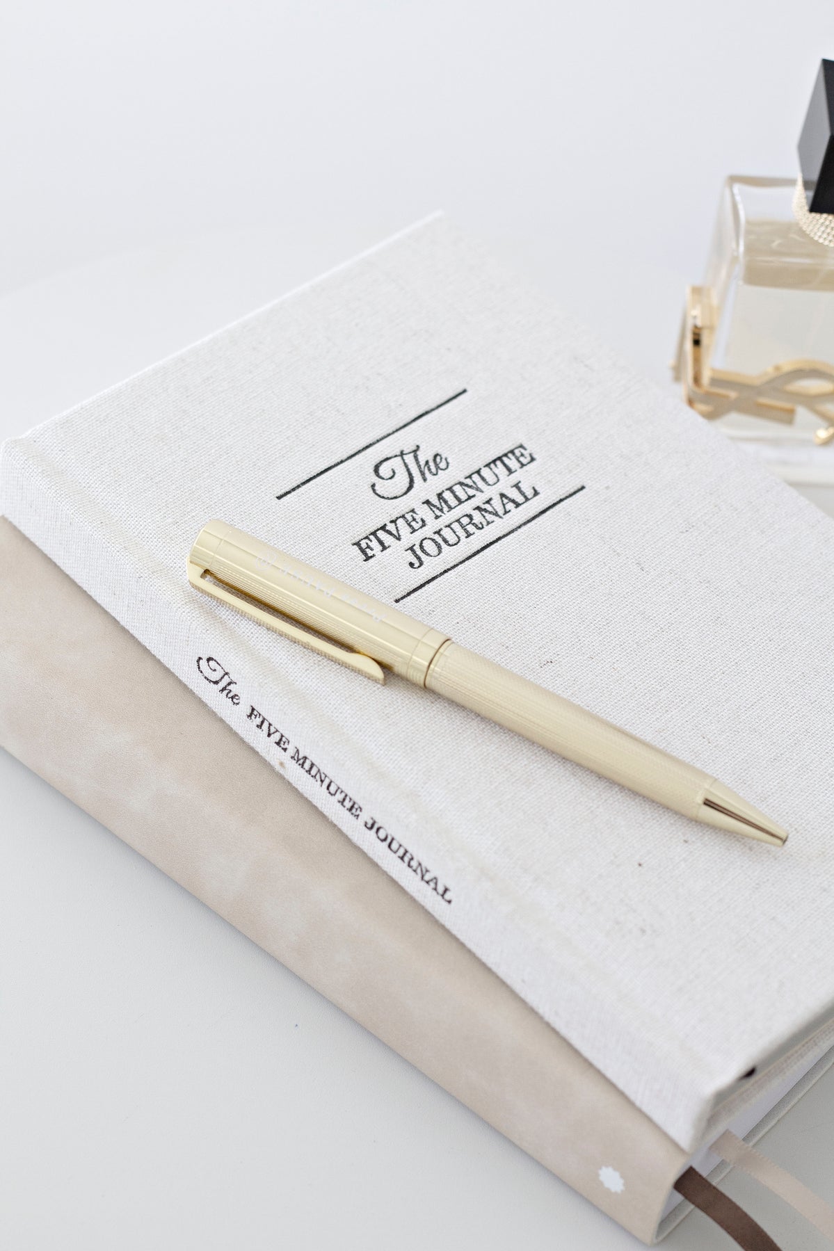 Open Five Minute Journal with a gold pen on a white desk