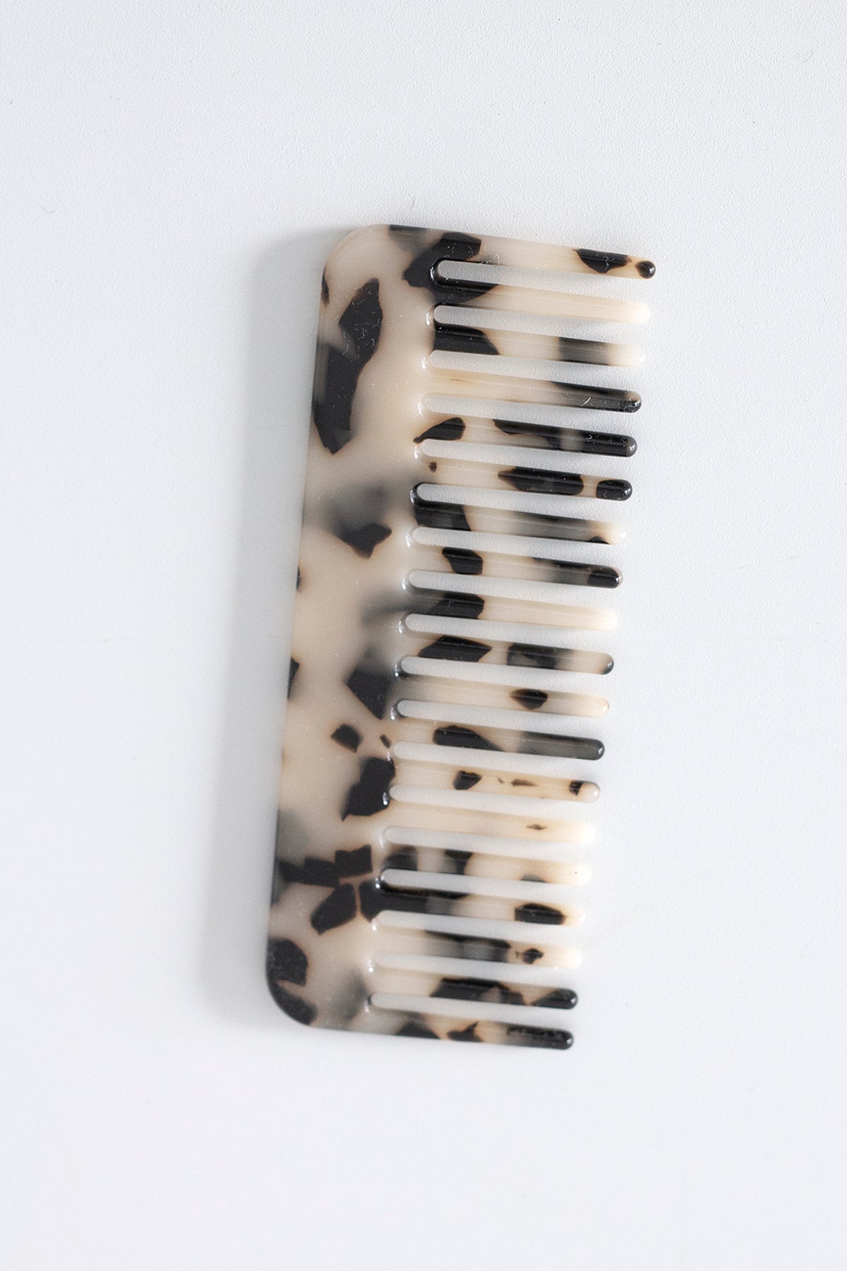 Light tortoiseshell acetate comb on a pale grey background, wide tooth