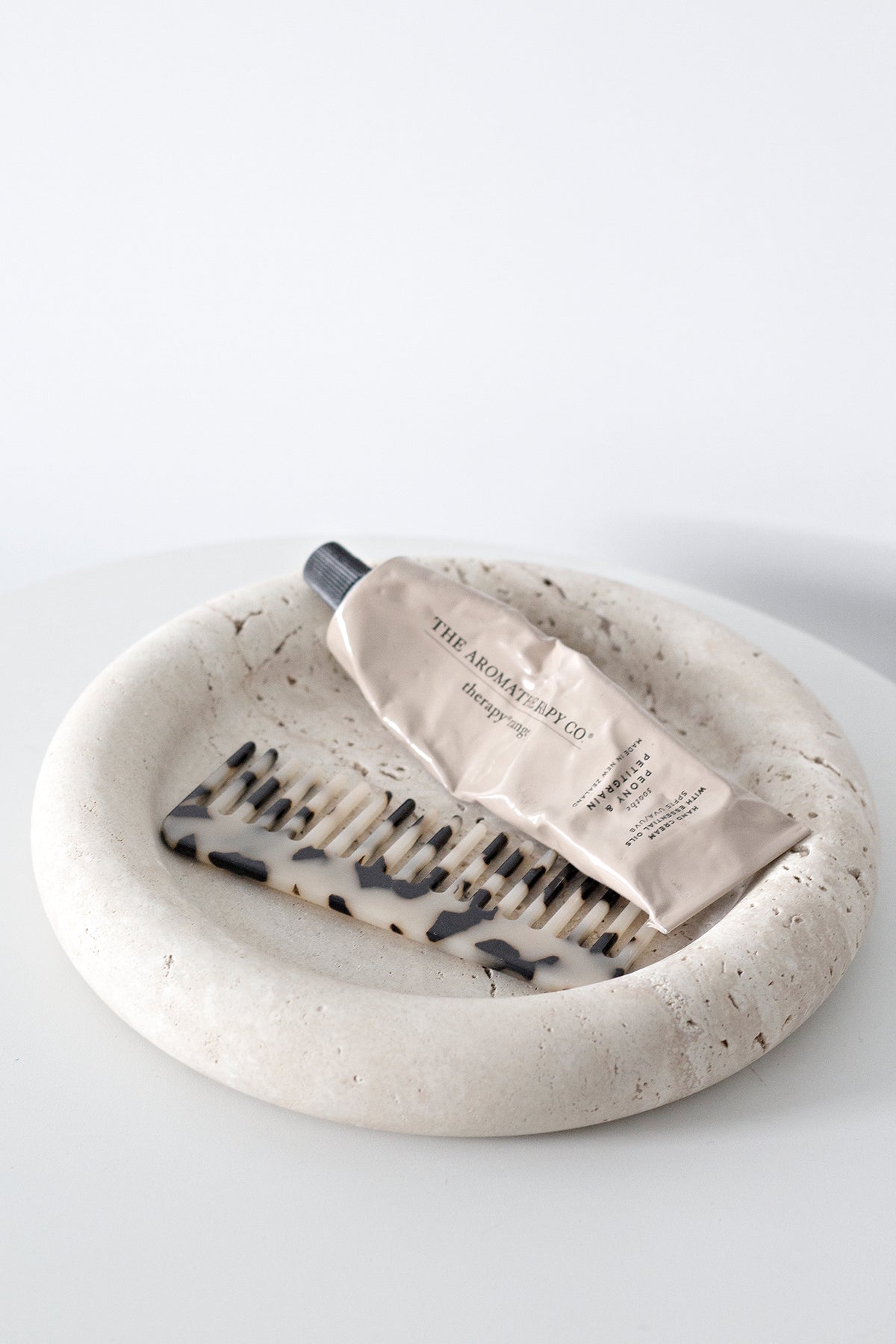 Pink and cream acetate combs together in a round travertine dish