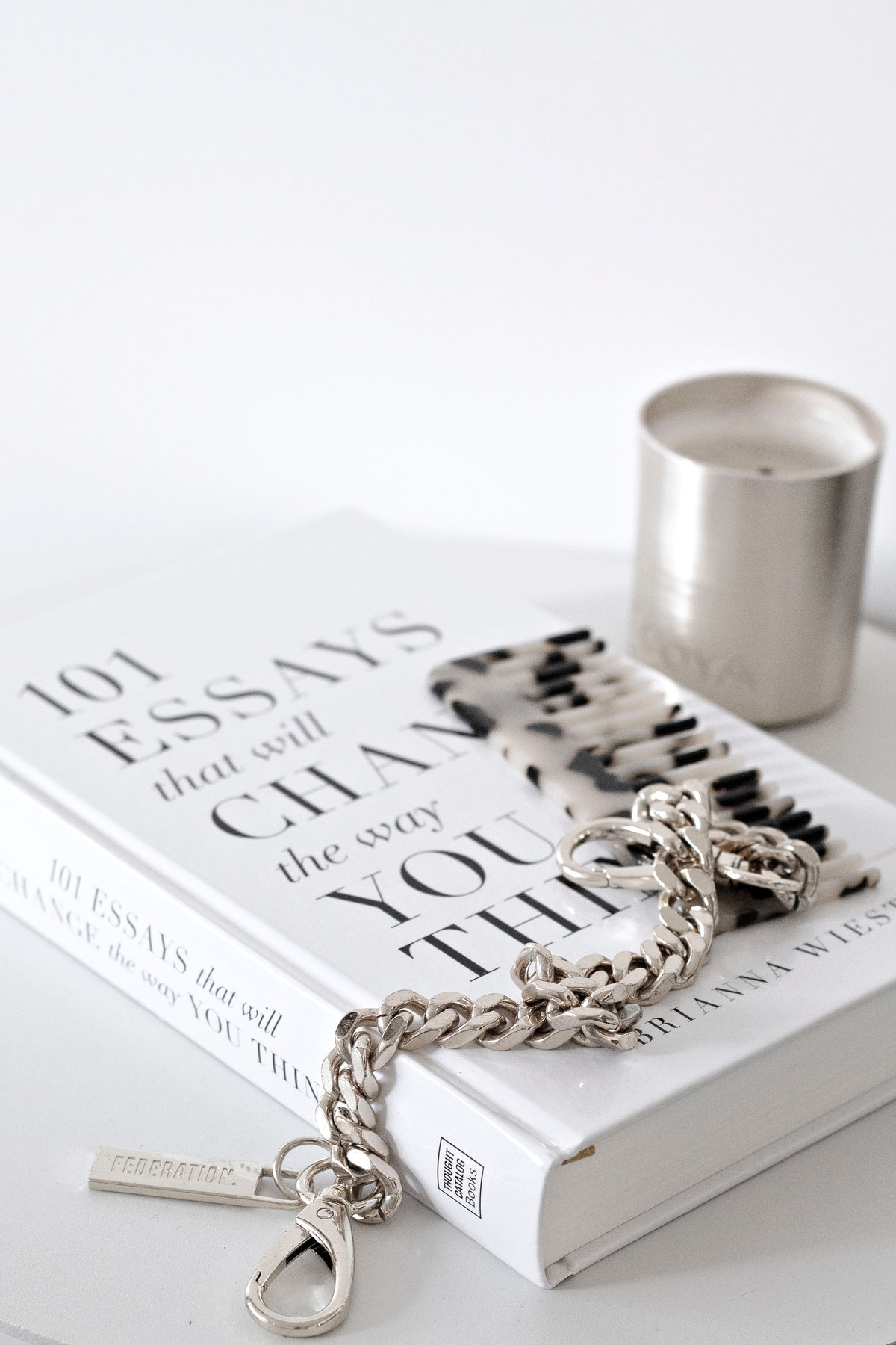 Black and white acetate comb with a silver chain bracelet on stacked books